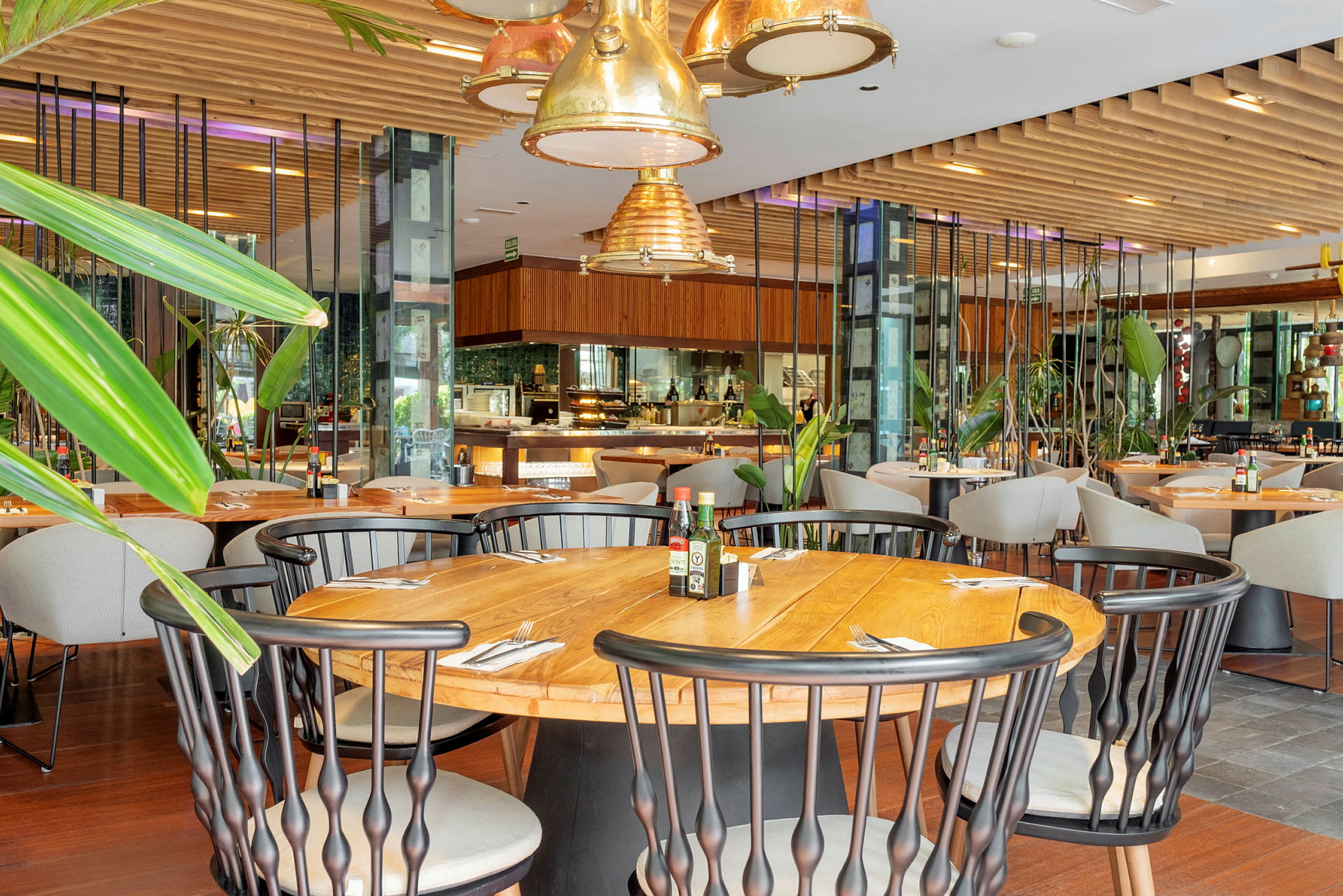 Interiör av en restaurang med träbord, stolar och grönskande dekorationer. (AI-genererad text)