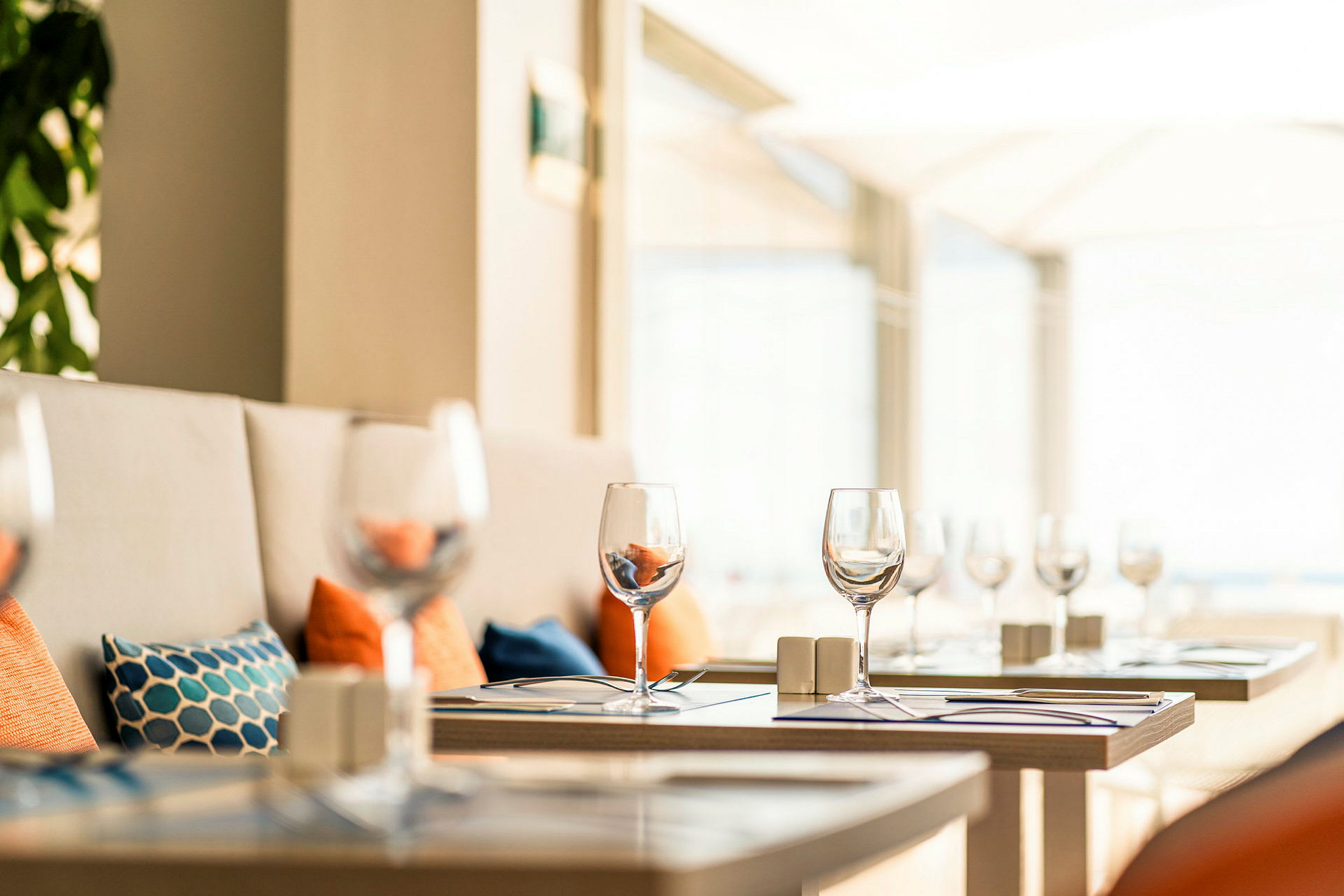 Ett dukat bord med vinglas i en restaurang med ljus inredning. (AI-genererad text)