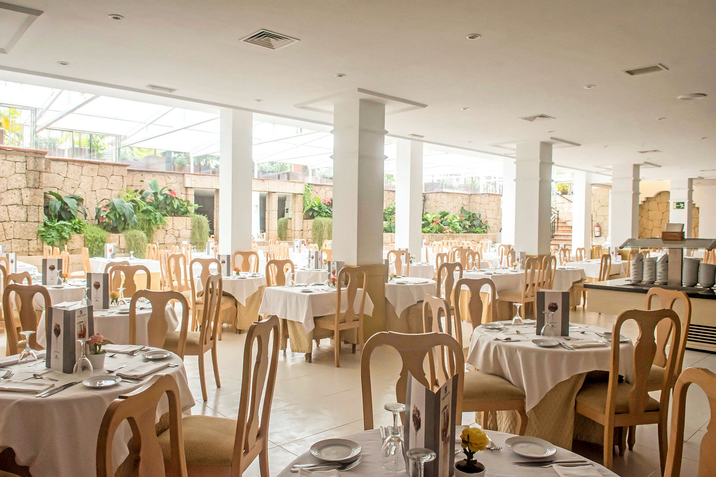 Ljus restaurang med dukade bord och trästolar. (AI-genererad text)