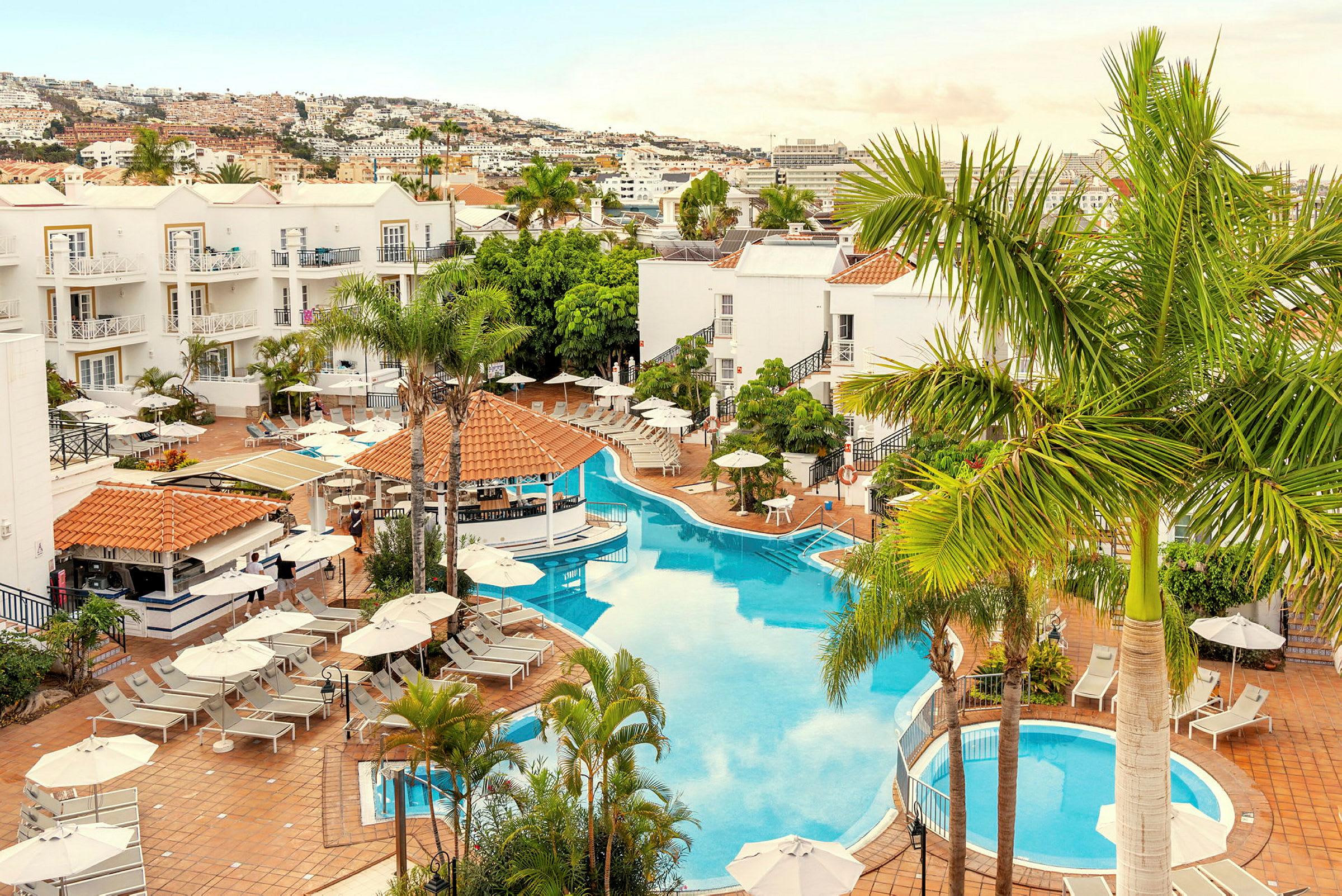 Bild av hotellområde med pool, solstolar och omgivande palmer. (AI-genererad text)