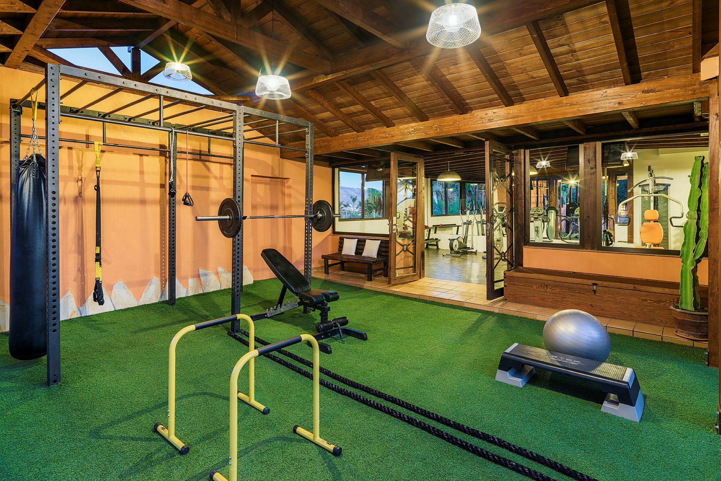 Ett gym med träningsutrustning såsom skivstång, ribbstol och stepbräda på en konstgräsmatta. (AI-genererad text)