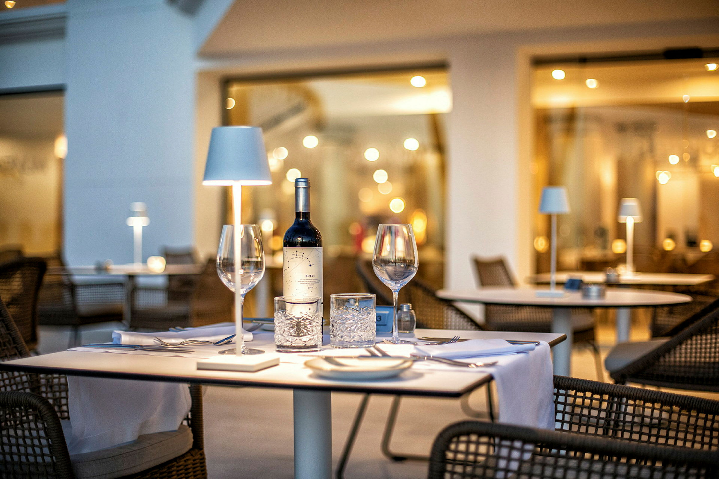 Ett dukat bord med en vinflaska och glas på en restaurang. (AI-genererad text)