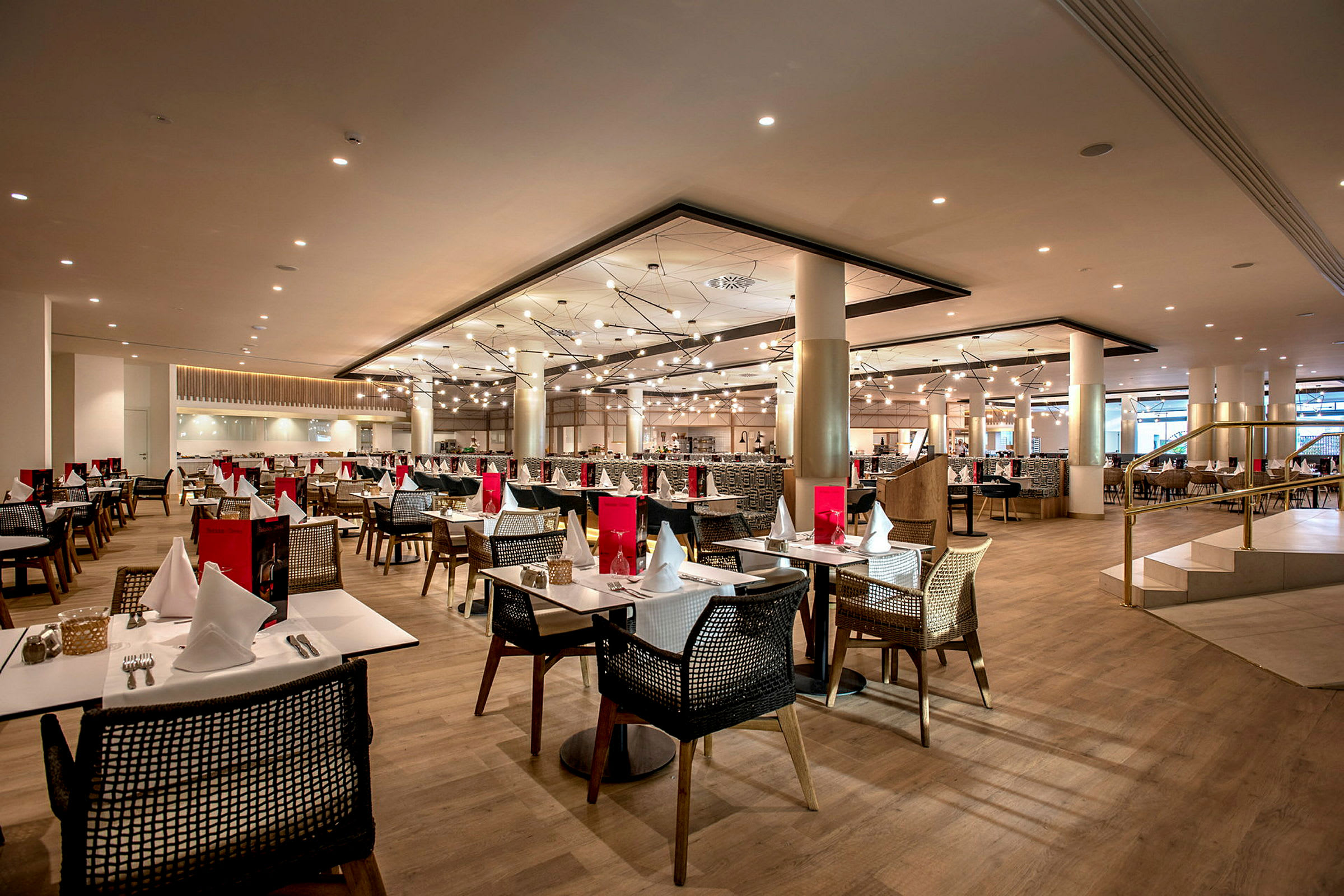 Bild av en restaurang med flera dukade bord och stolar i en modern inomhusmiljö. (AI-genererad text)
