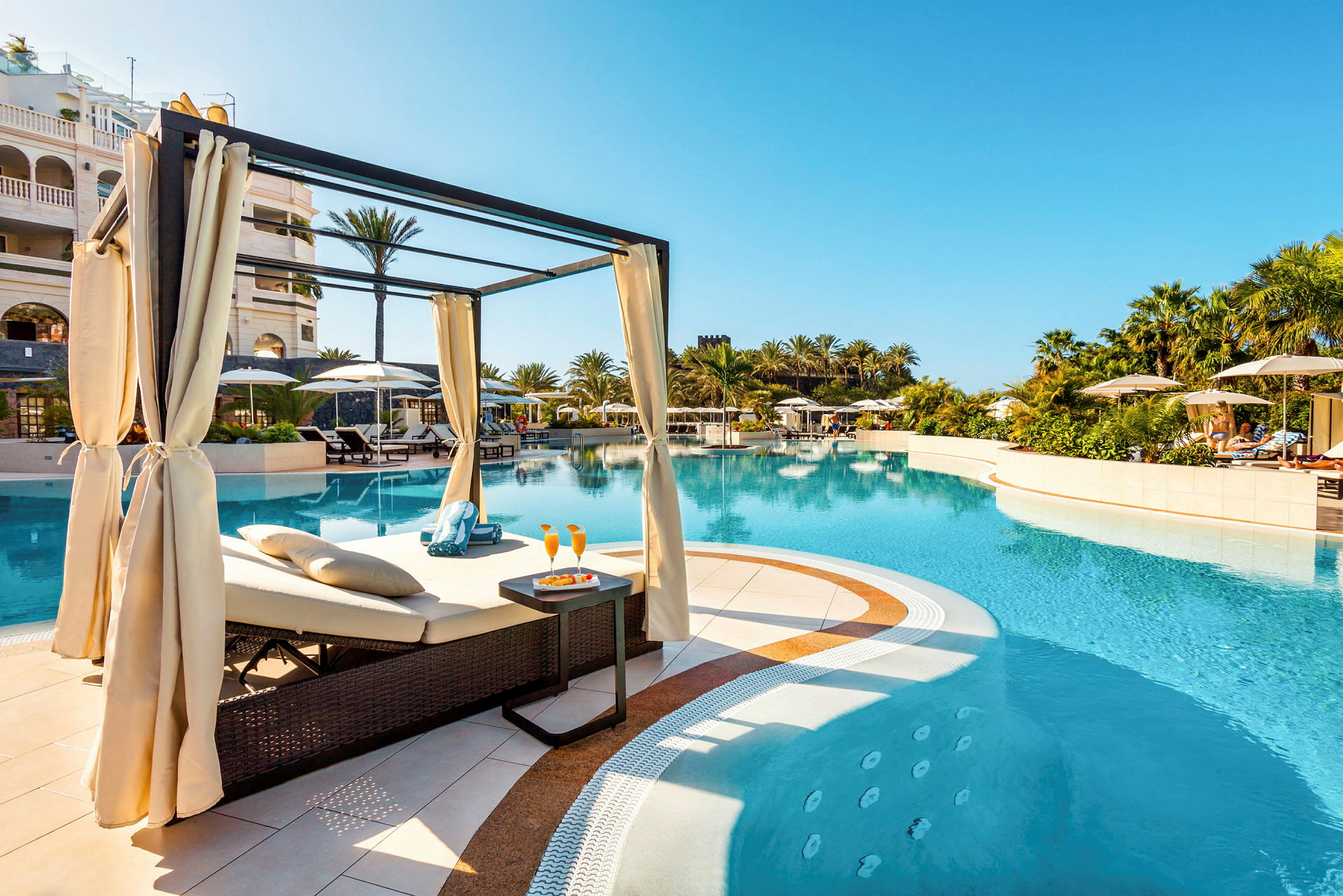 Hotellpool med solstolar och parasoller, omgiven av palmer. (AI-genererad text)
