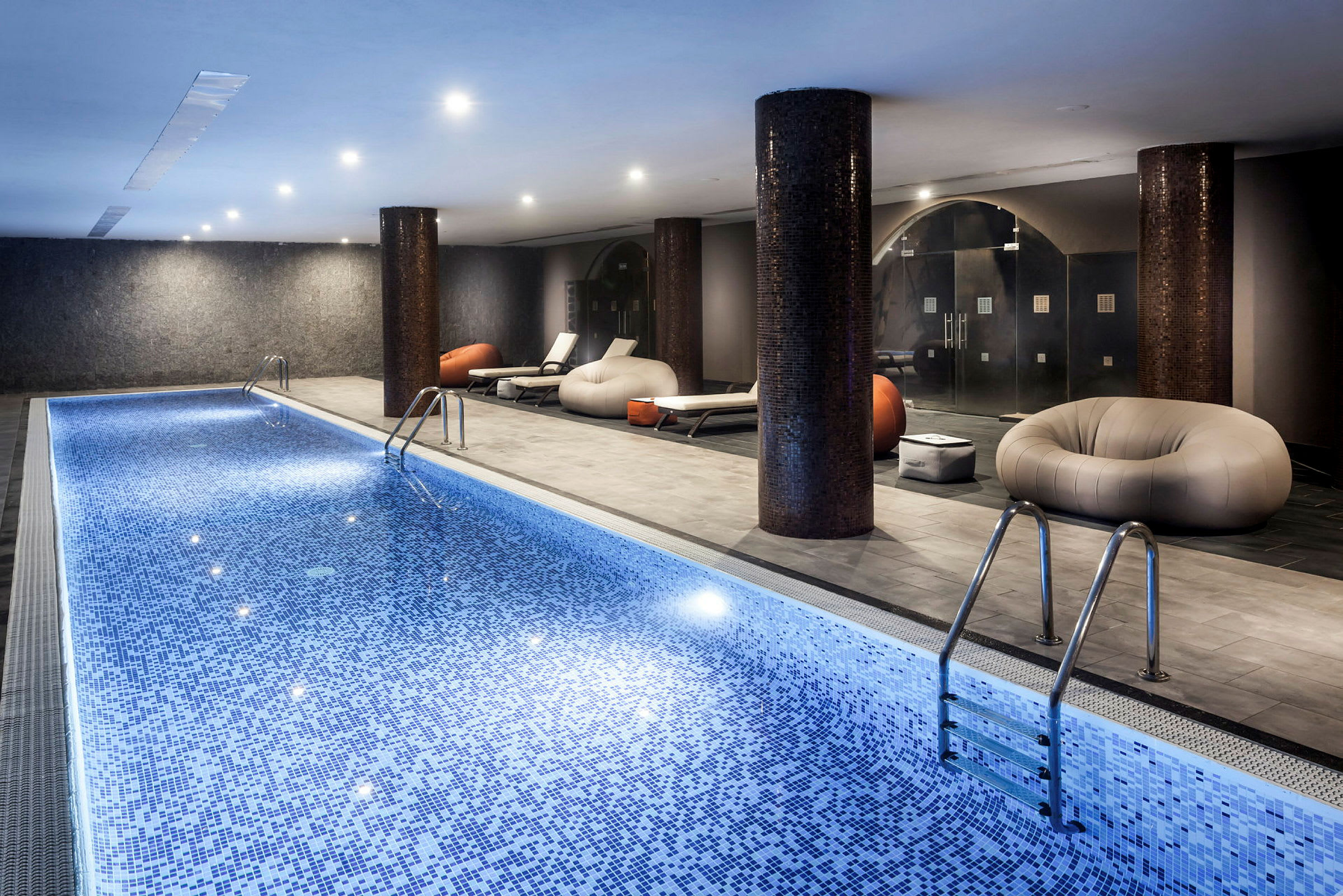 Inomhuspool med loungemöbler och belysning. (AI-genererad text)