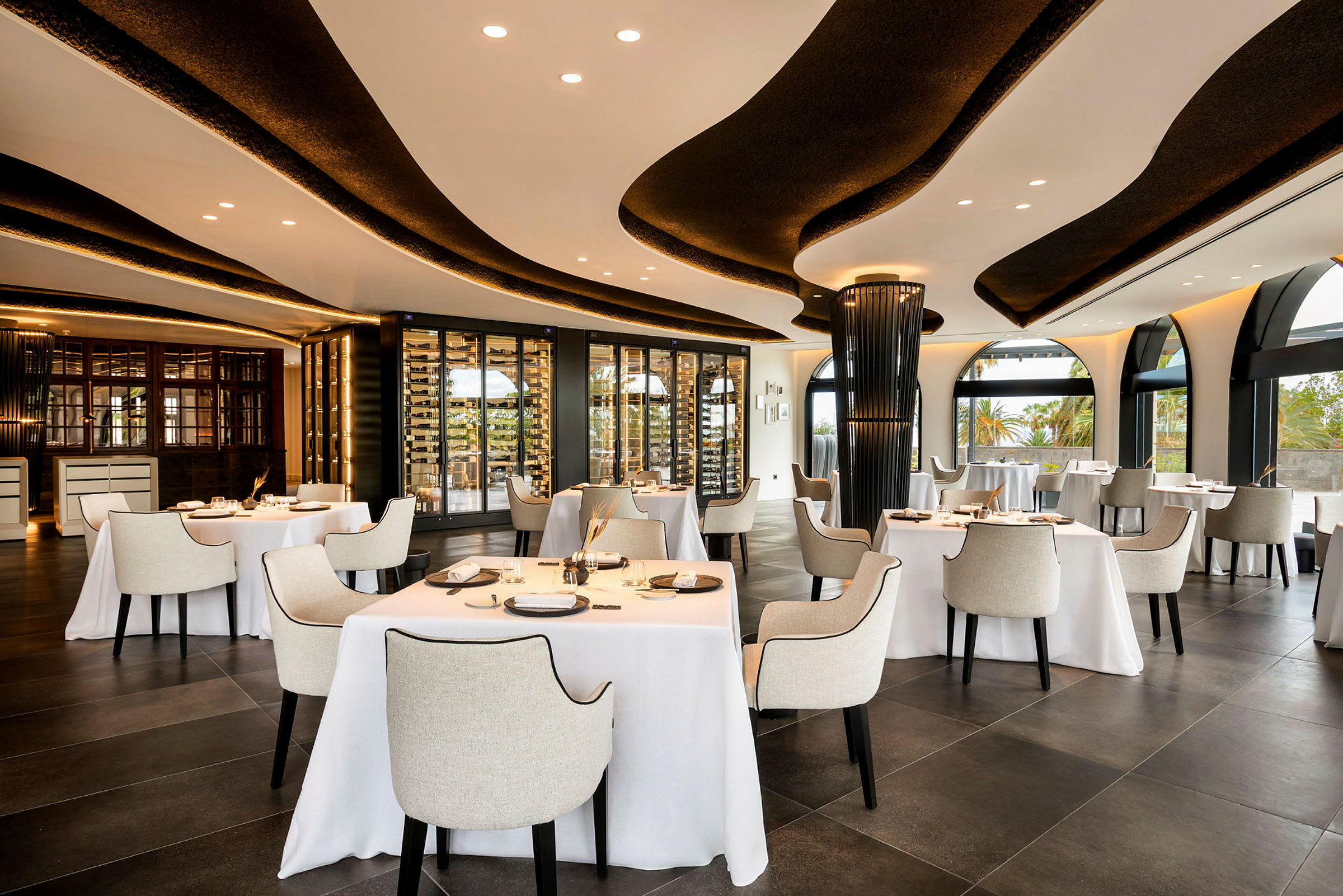 Bild av en elegant restaurang med bordsdukade bord och stolar, stora fönster och modern inredning. (AI-genererad text)