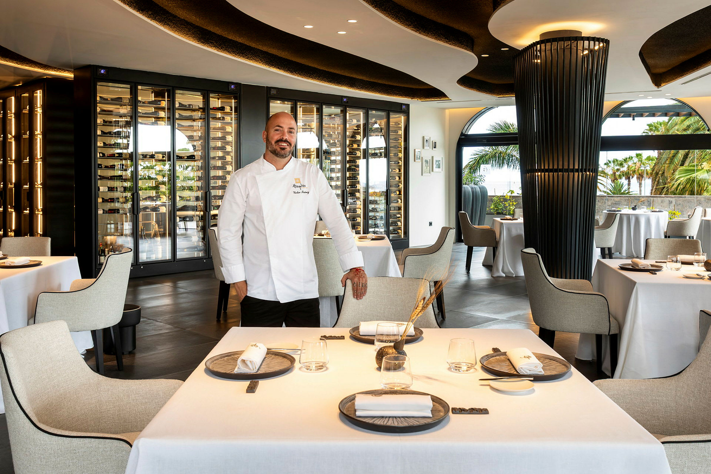 Interiör av en elegant restaurang med dukade bord och en vinförvaring i bakgrunden. (AI-genererad text)