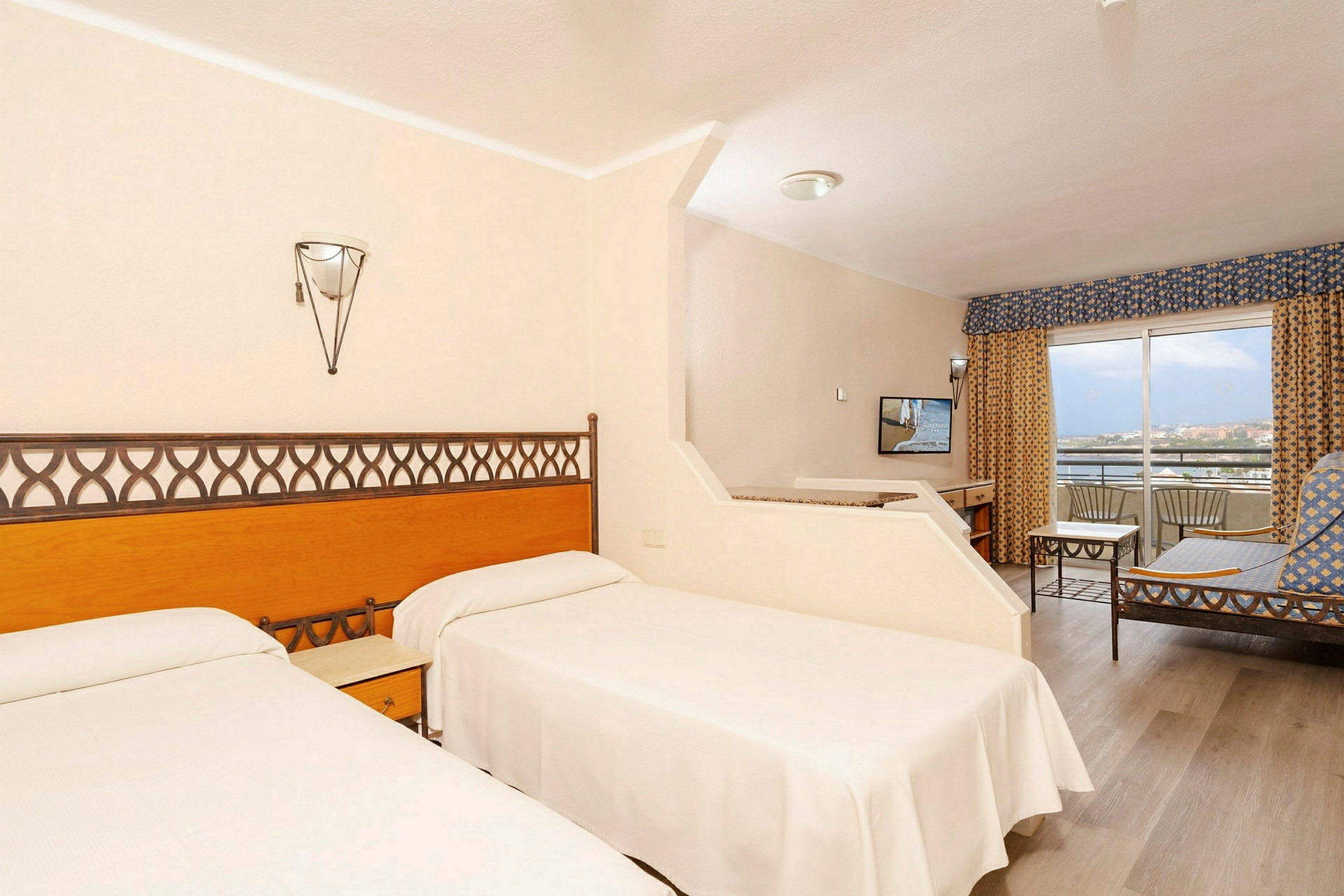 Hotellrum med två enkelsängar, sittgrupp och balkong. (AI-genererad text)