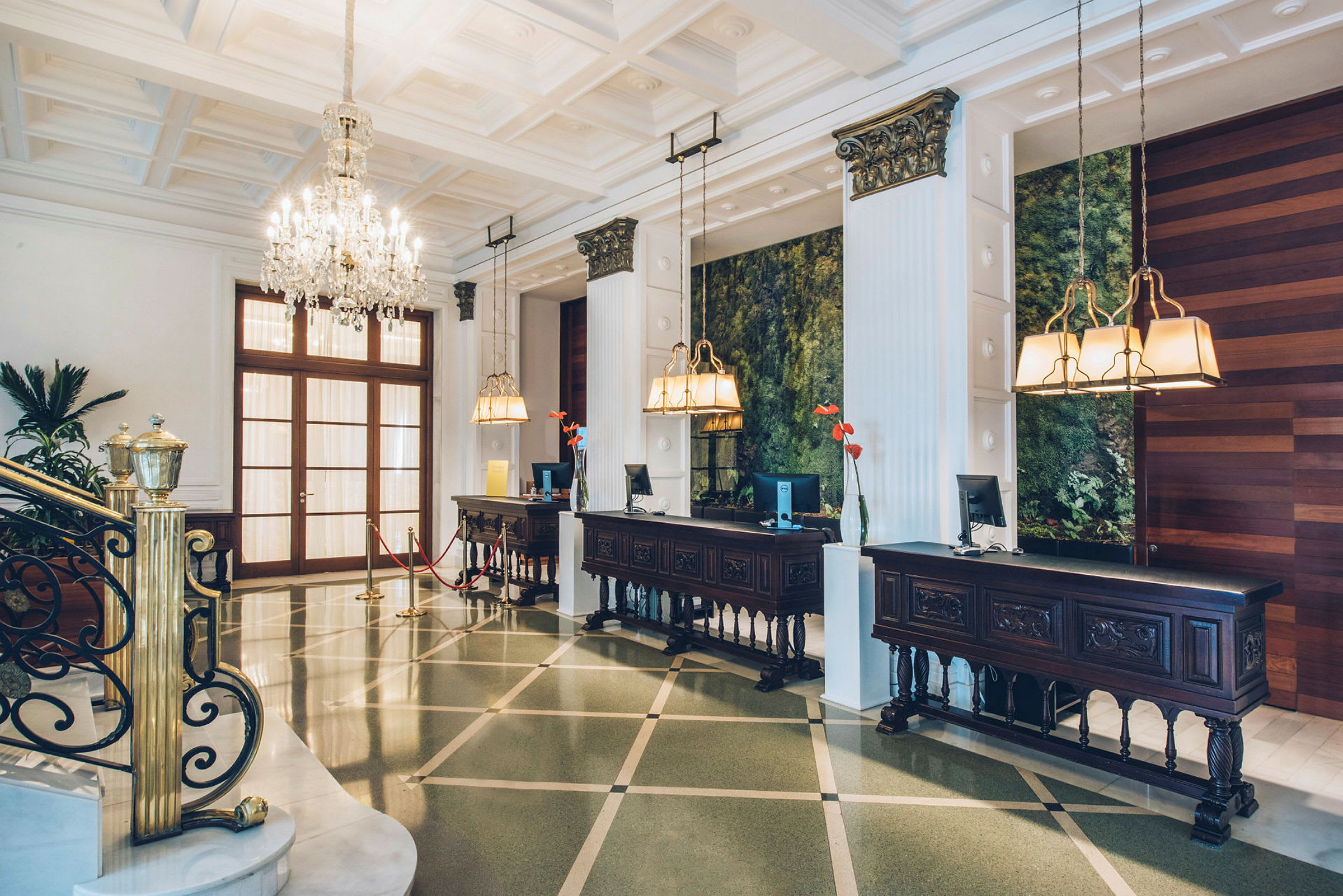 Hotellets reception med eleganta möbler, ljuskronor och ett grönt dekorerat område i bakgrunden. (AI-genererad text)