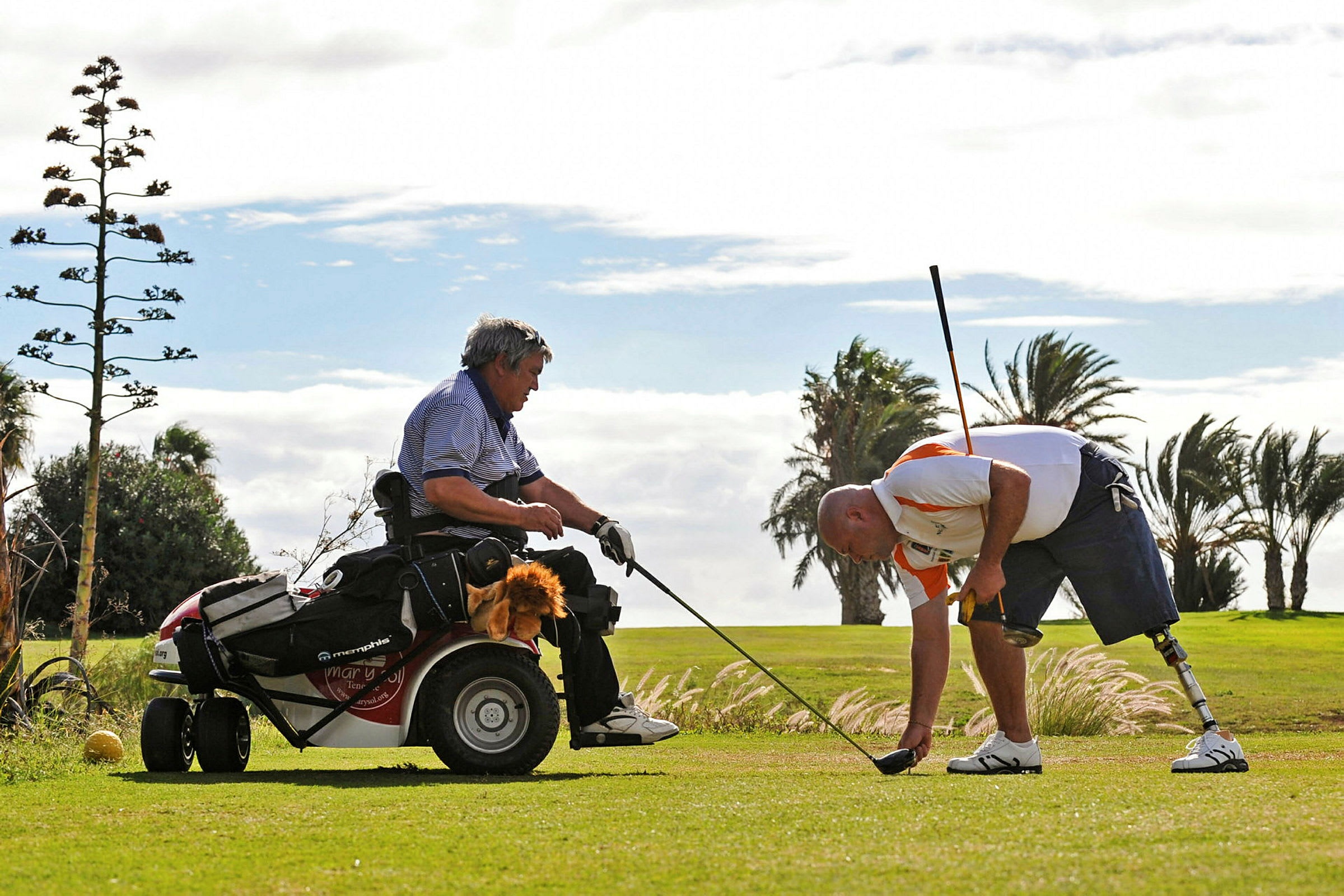 Två personer spelar golf, en sitter i en golfkärra och en annan böjer sig ner på gräsmattan med en golfklubba. (AI-genererad text)