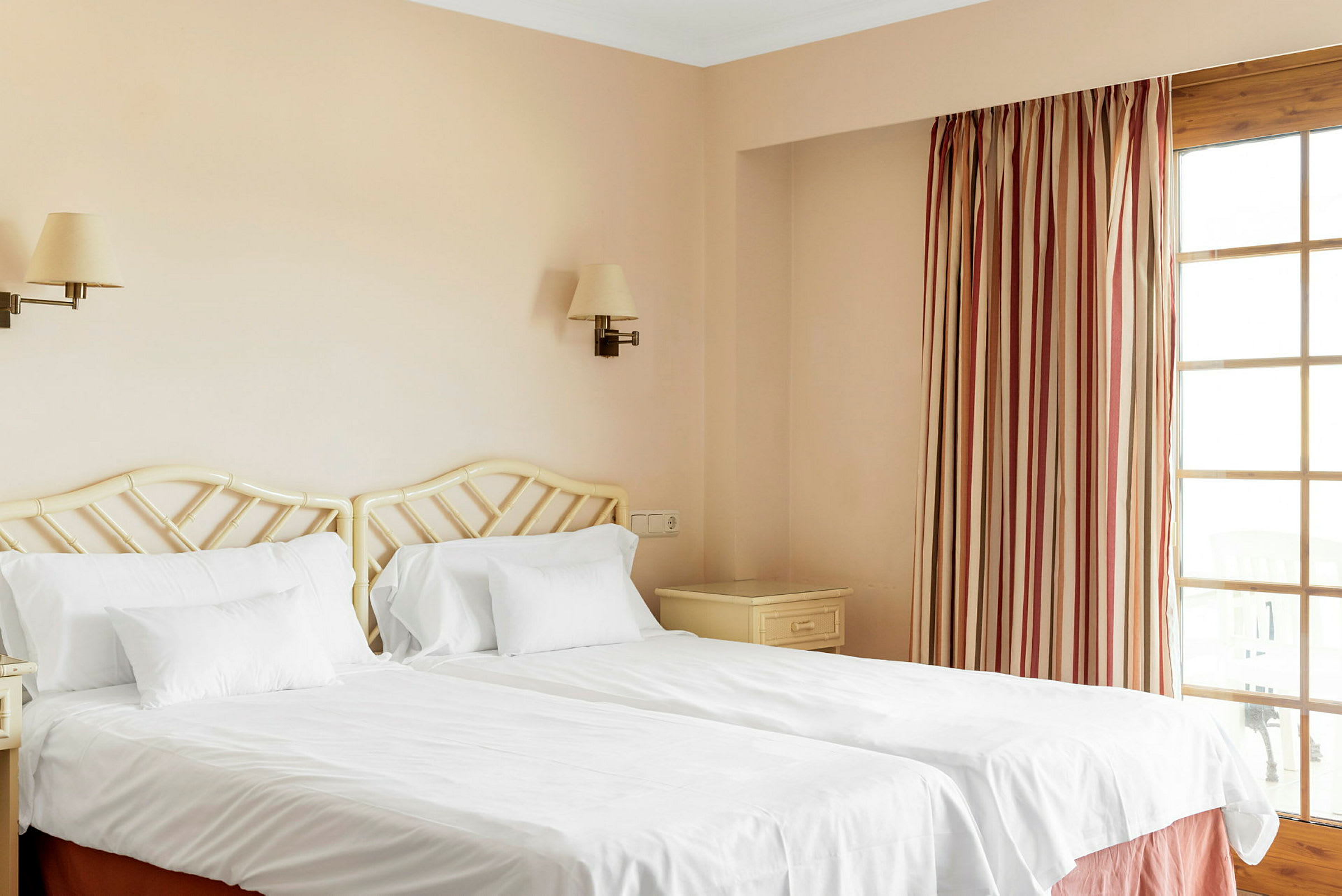 Två enkelsängar med vita sängkläder i ett hotellrum. (AI-genererad text)