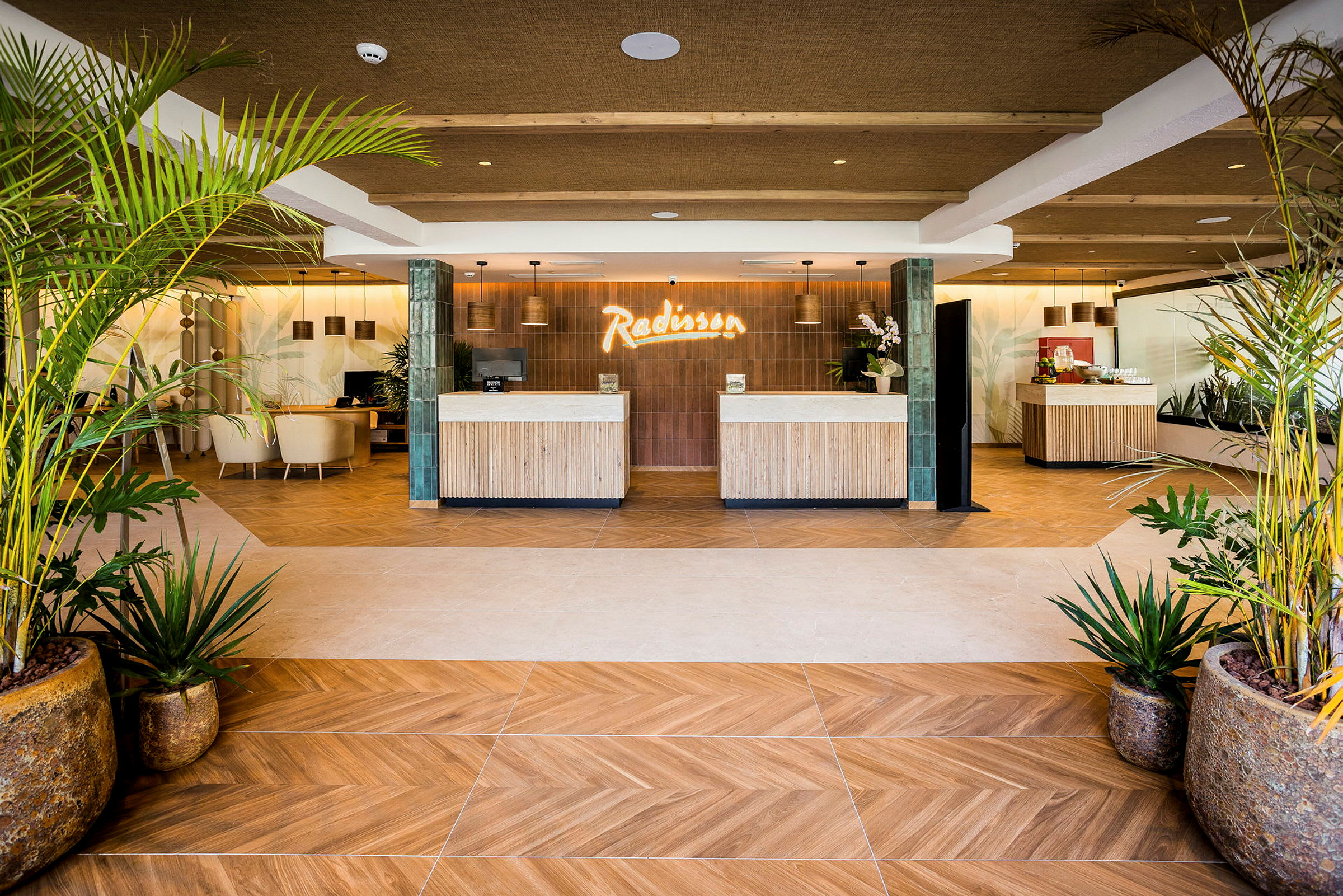Lobbyn på ett hotell med receptionsdiskar dekorerade med träpaneler. Gröna växter pryder rummet. (AI-genererad text)