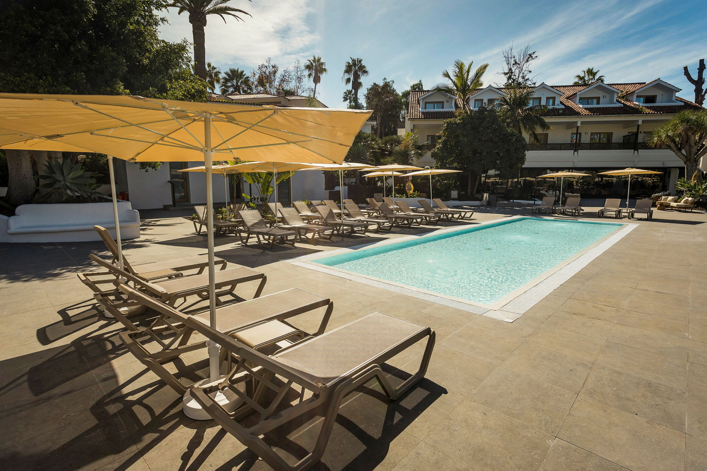 Utomhuspool med solstolar och parasoller i en hotellmiljö. (AI-genererad text)