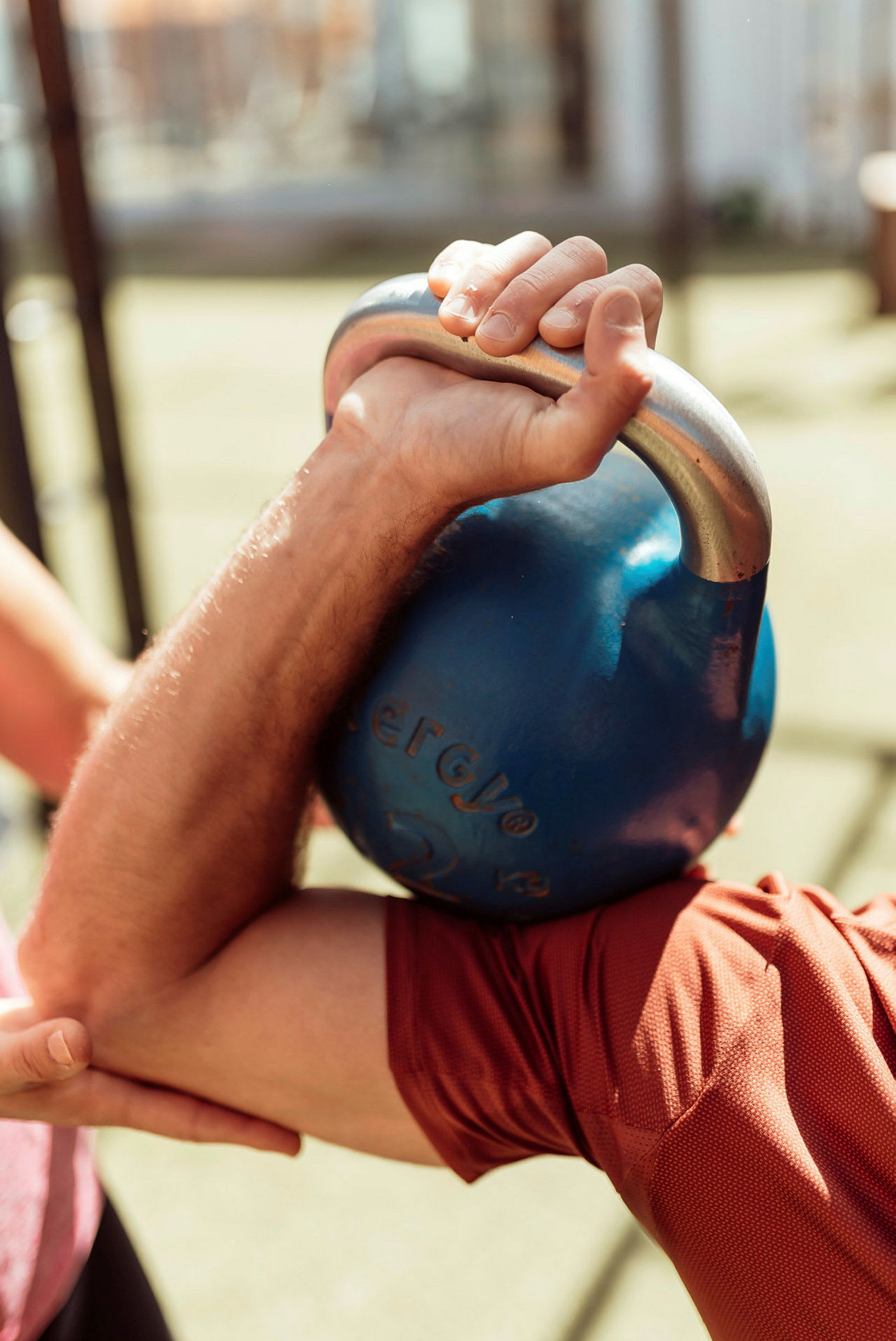 En arm håller en blå kettlebell under träning. (AI-genererad text)