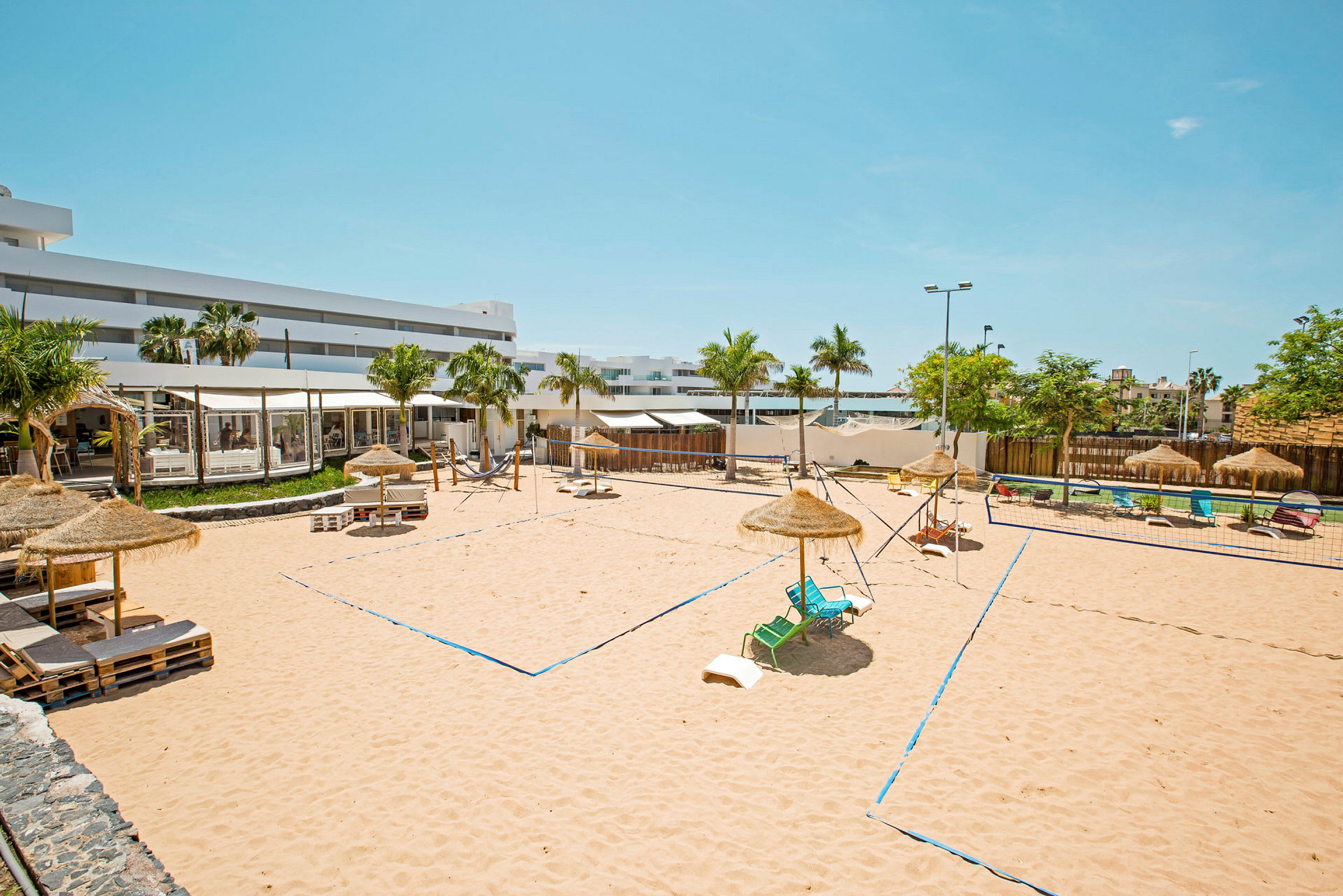 Bild på en sandig volleybollplan med parasoller och solstolar runt om. (AI-genererad text)