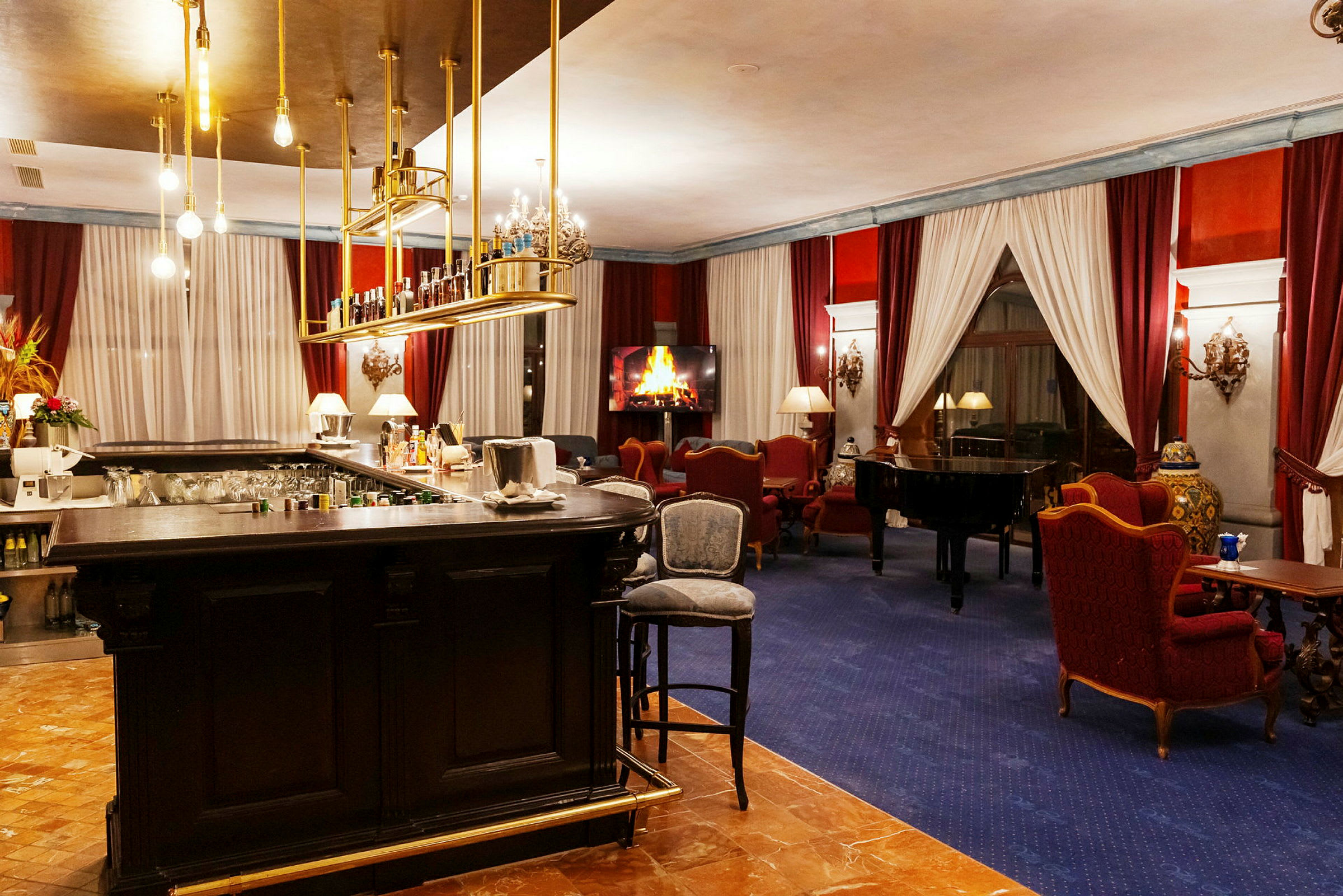 En elegant hotellounge med en bardisk, en piano och sittgrupper framför ett digitalt brinnande eldstad. (AI-genererad text)