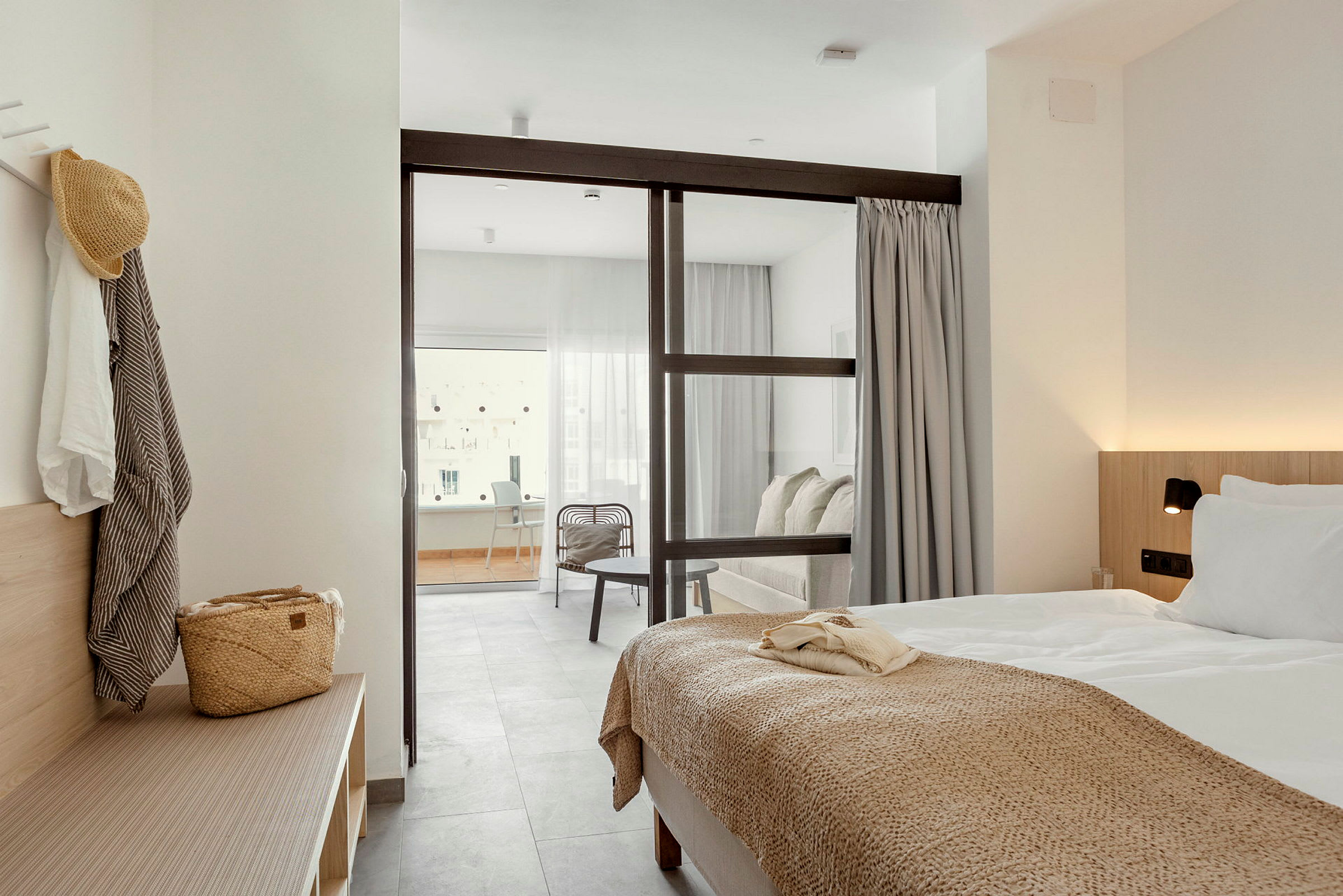 Ett hotellrum med en säng och sittgrupp separerade av en glasvägg. (AI-genererad text)