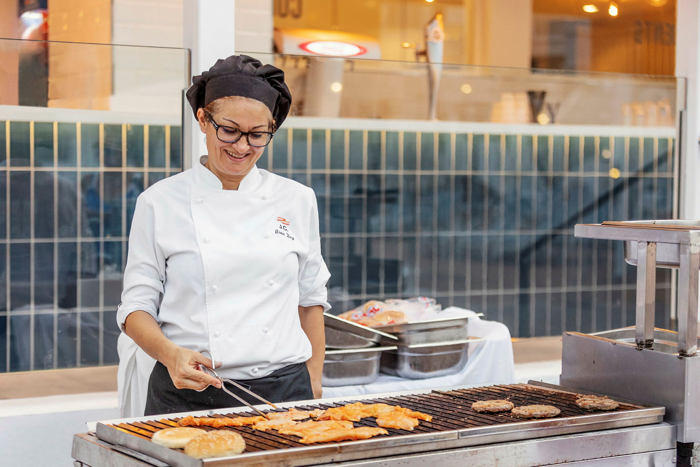 En kock vid en grillstation som lagar hamburgare och kött. (AI-genererad text)