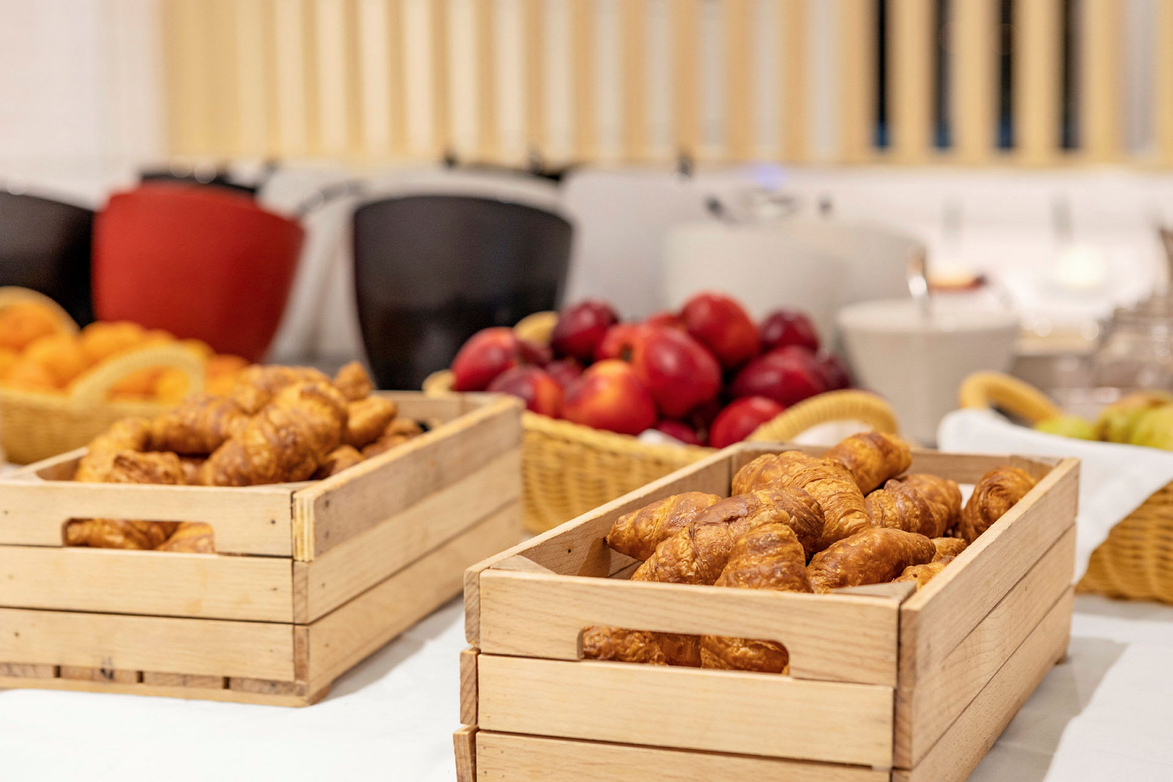 Trälådor med croissanter och frukt på ett bord. (AI-genererad text)