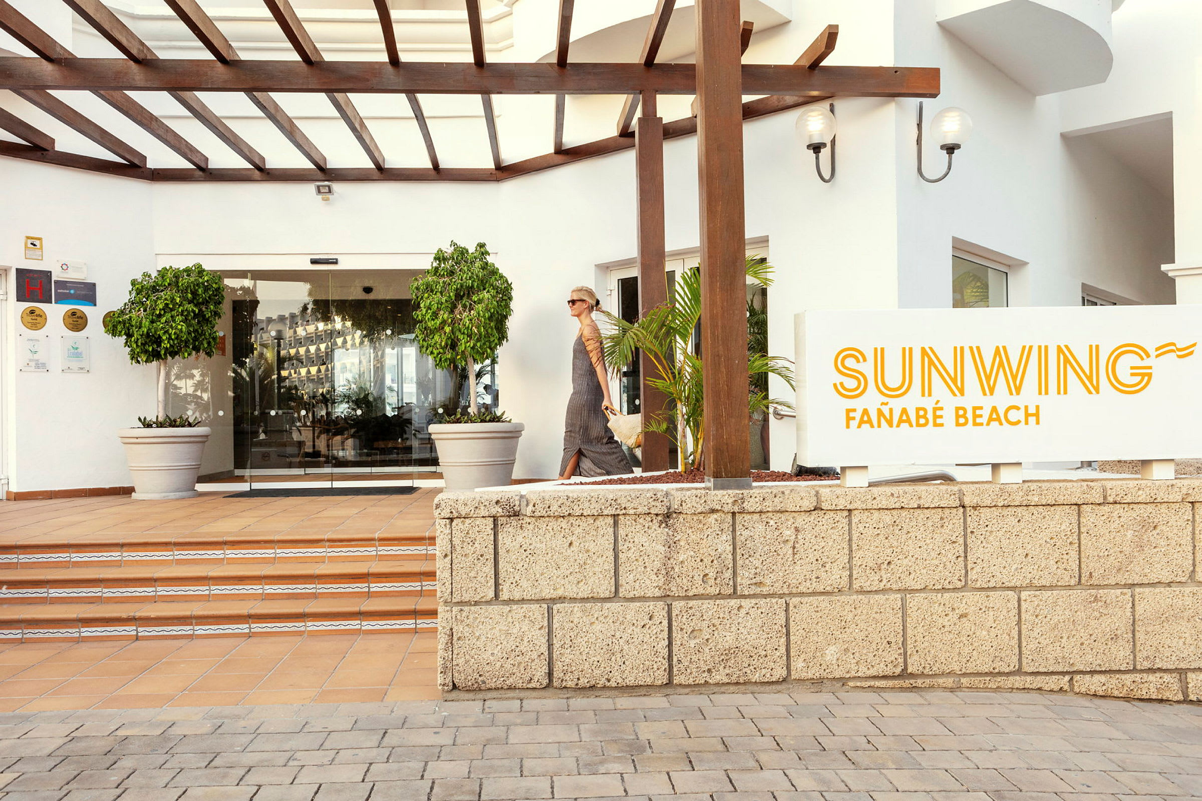 Entrén till Sunwing Fañabé Beach med skylt och glasdörrar. (AI-genererad text)