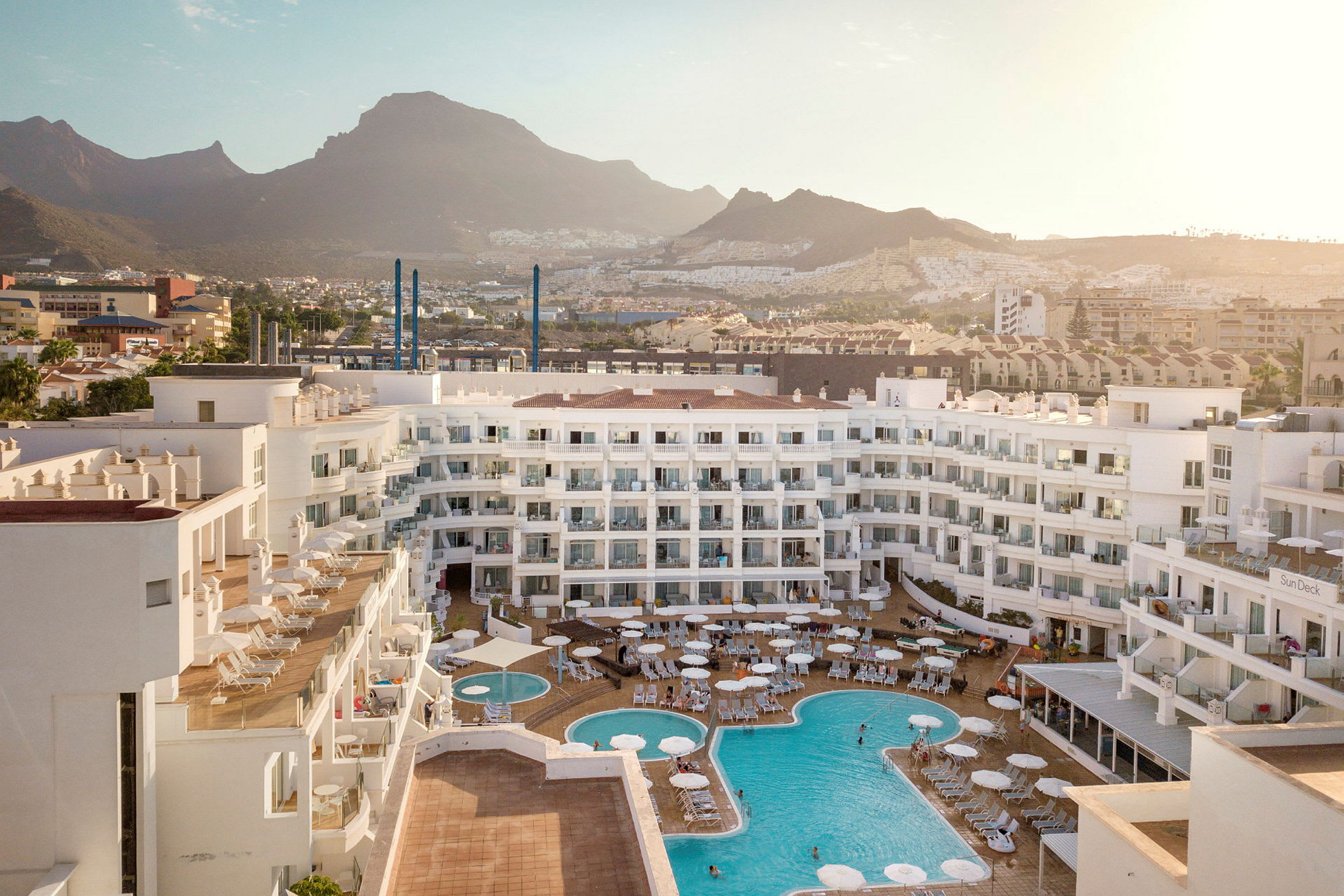 Vy över hotellområde med pooler och omgivande berg. (AI-genererad text)