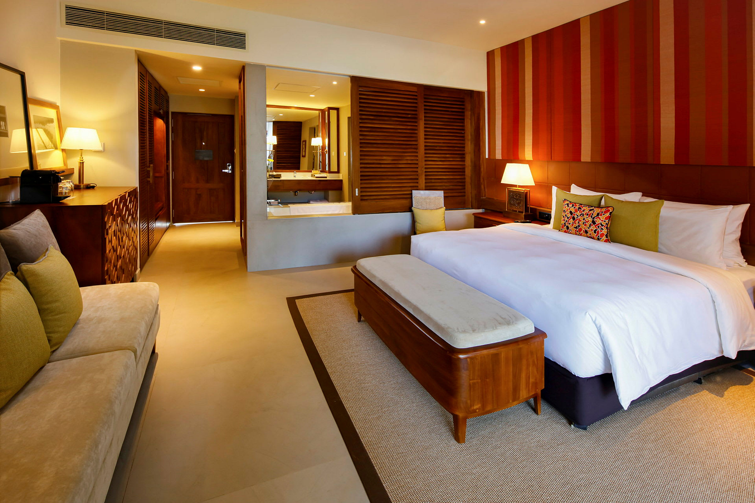 Ett hotellrum med en stor säng, en soffa, ett skrivbord och en modern inredning. (AI-genererad text)