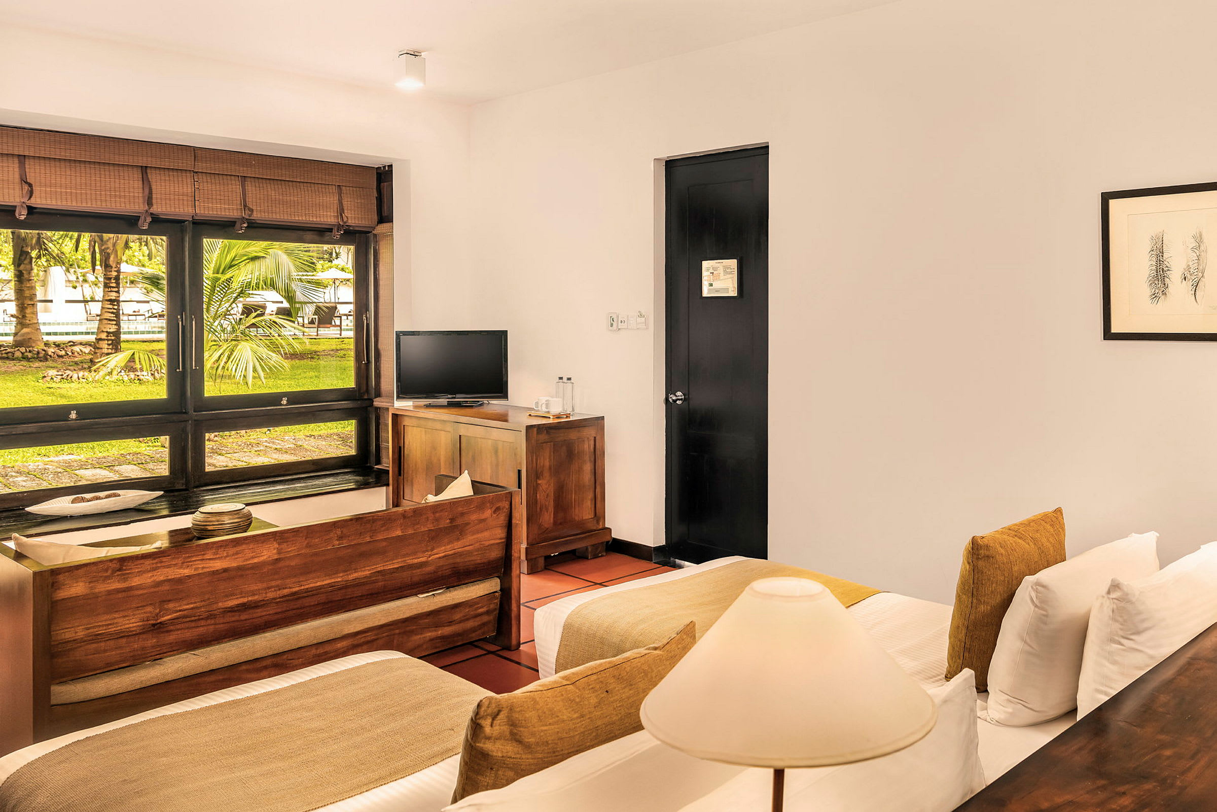 Hotellrum med två bäddar, en TV och en fönstervy med grönska utanför. (AI-genererad text)