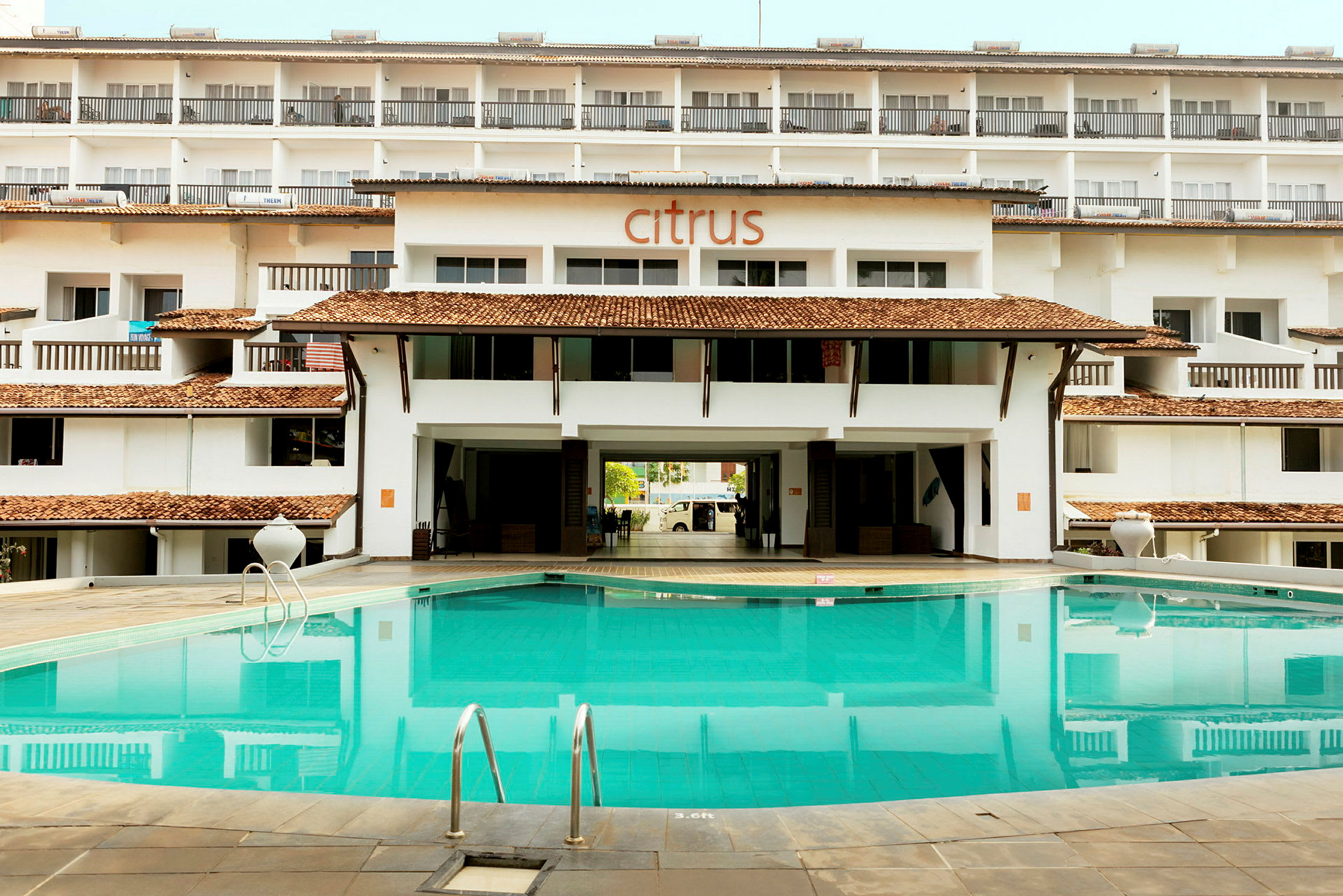 En pool framför en flerbostadsbyggnad med skylten "Citrus" på fasaden. (AI-genererad text)