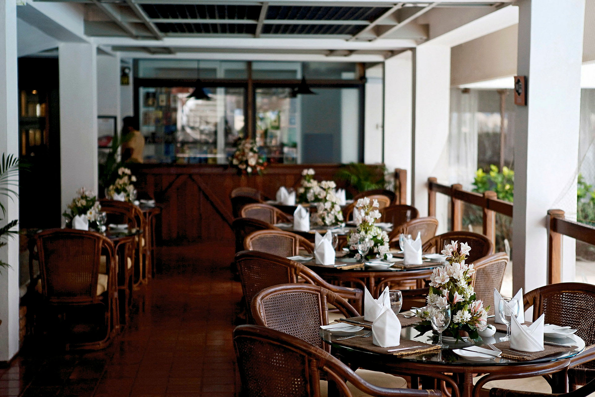 En restaurang med dukade bord och blommor på varje bord. (AI-genererad text)