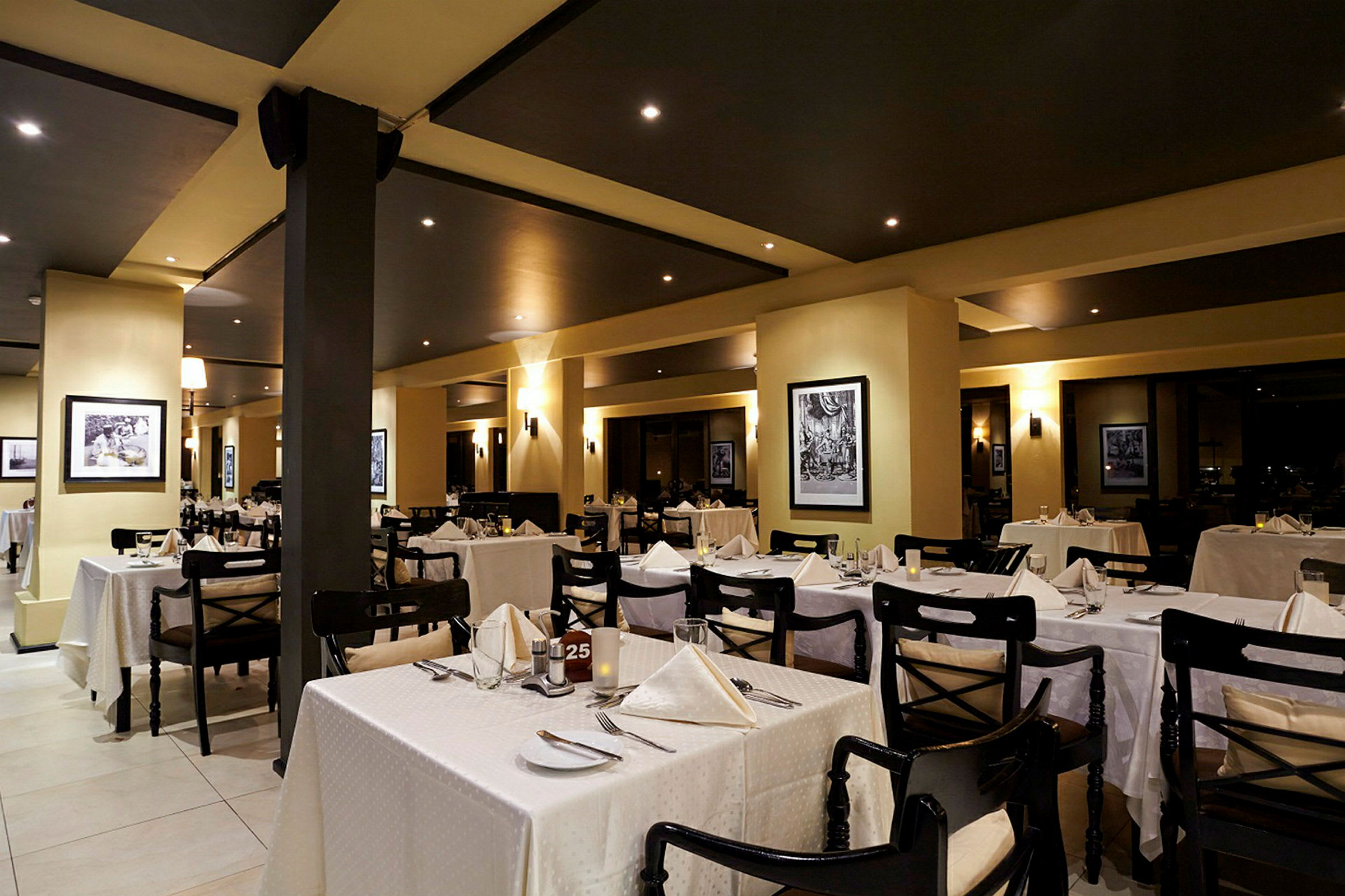 Interiör av en elegant restaurang med dukade bord och inramade konstverk på väggarna. (AI-genererad text)