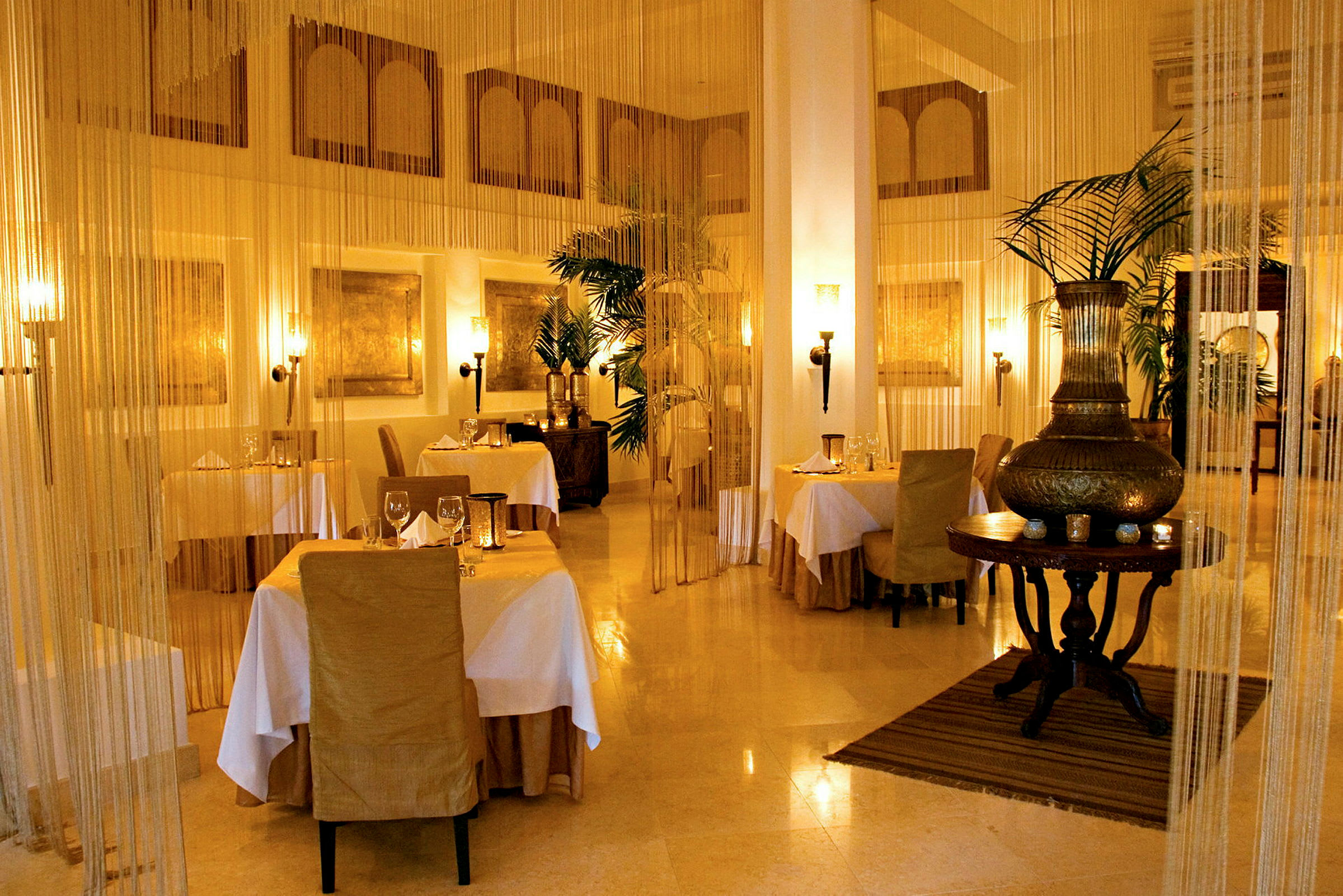 En elegant restaurang med dukade bord, stolar klädda i beige och ljus belysning. (AI-genererad text)