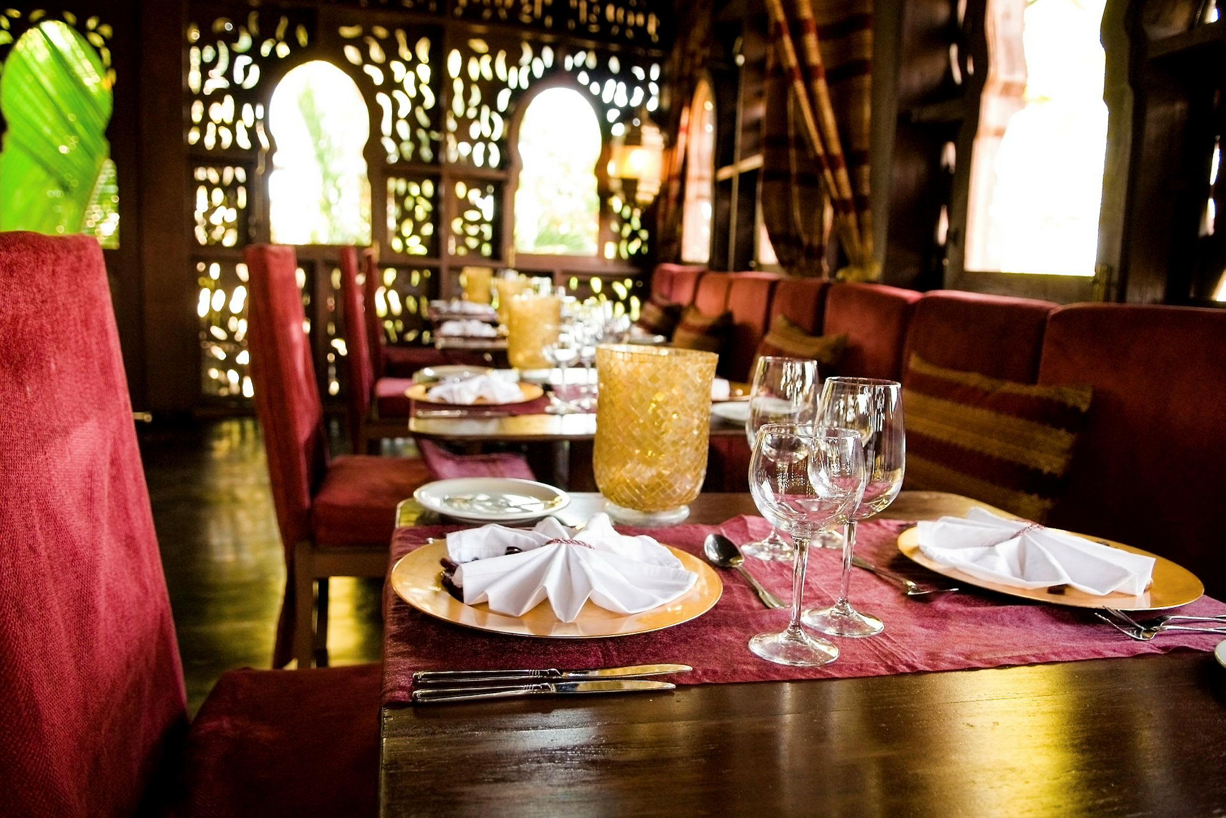 Ett bord i en elegant restaurang med röd inredning, dukat med tallrikar, glas och bestick. (AI-genererad text)