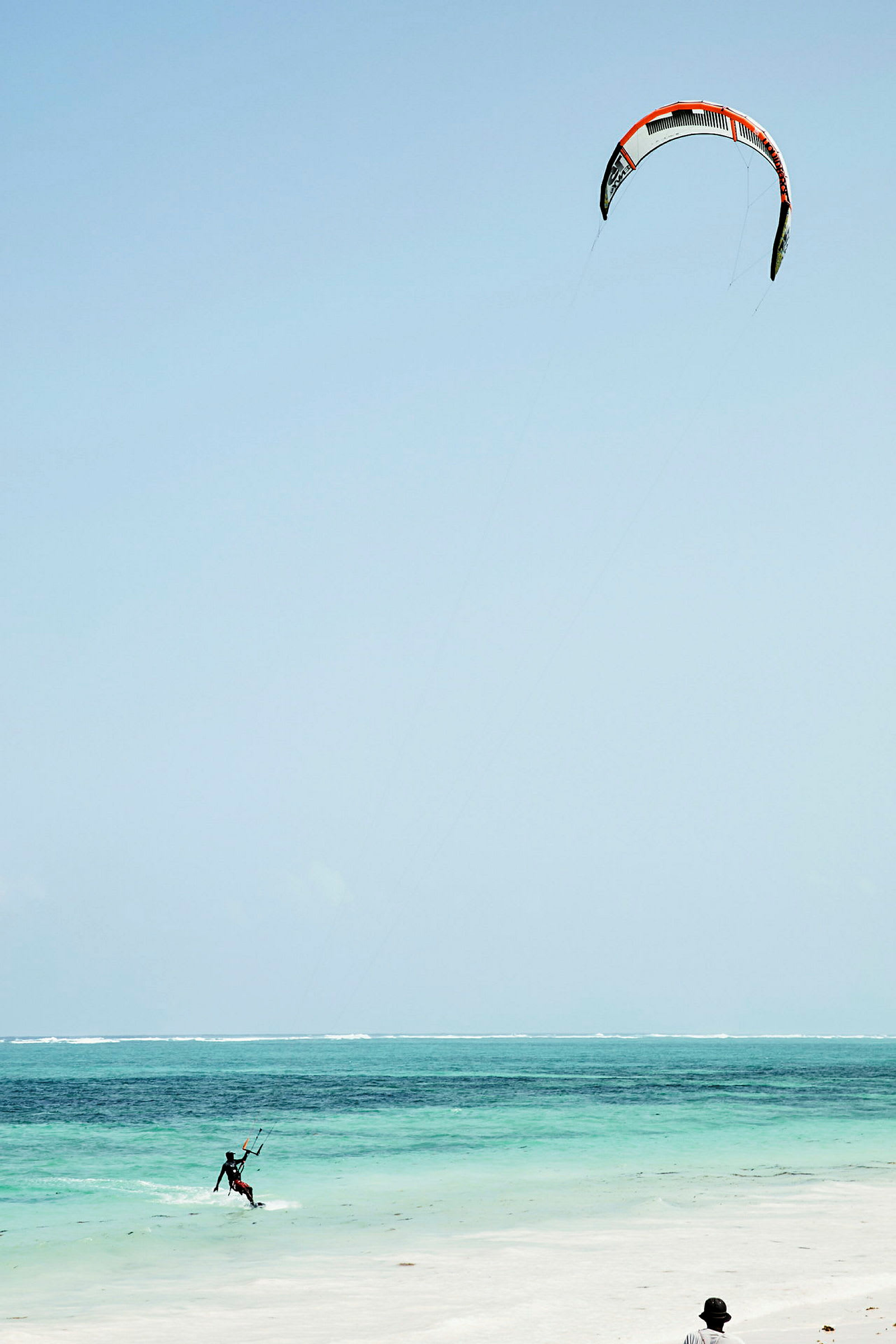 En person åker kitesurfing på en klarblå havsstrand. (AI-genererad text)