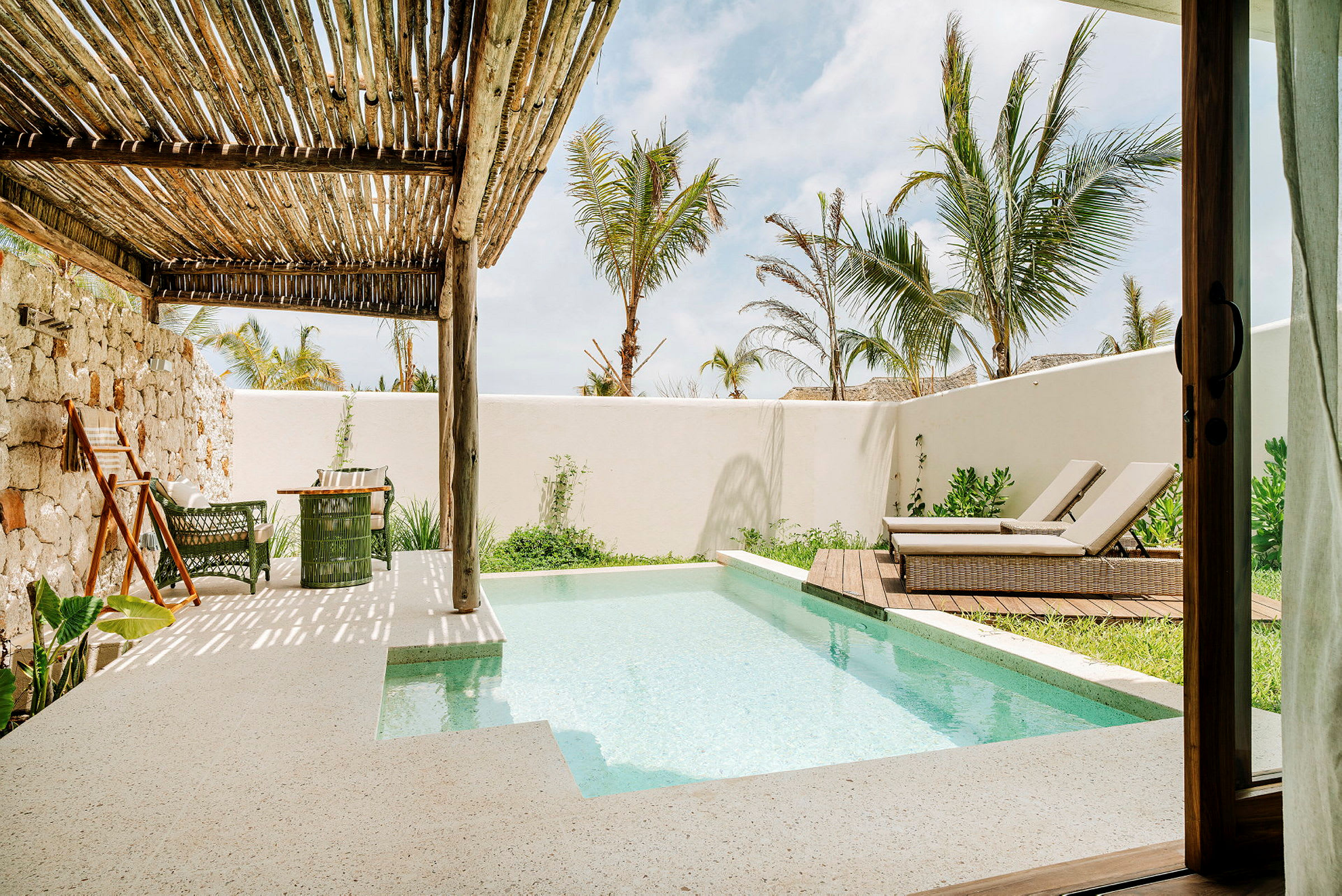 Terrass med liten pool, solstolar och växtlighet under ett träpergola. (AI-genererad text)