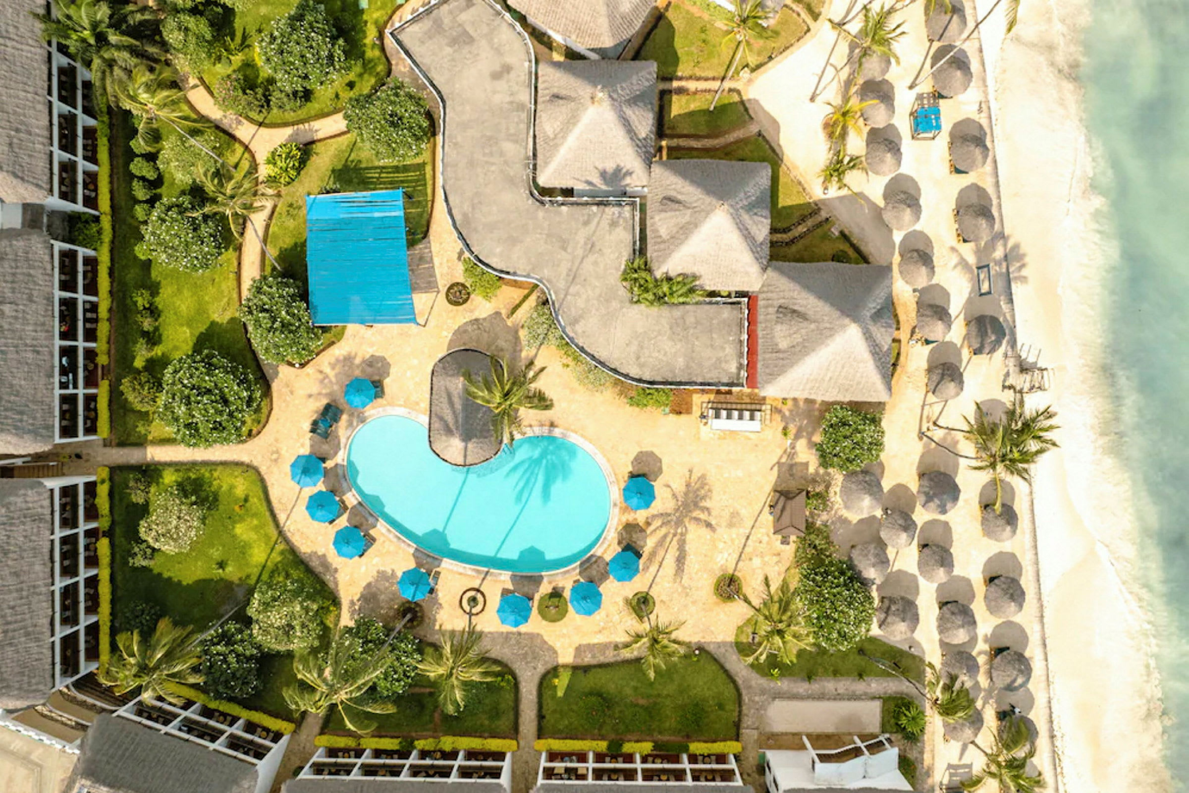 Översiktsbild av en resort med pool, parasoller, och strand. (AI-genererad text)