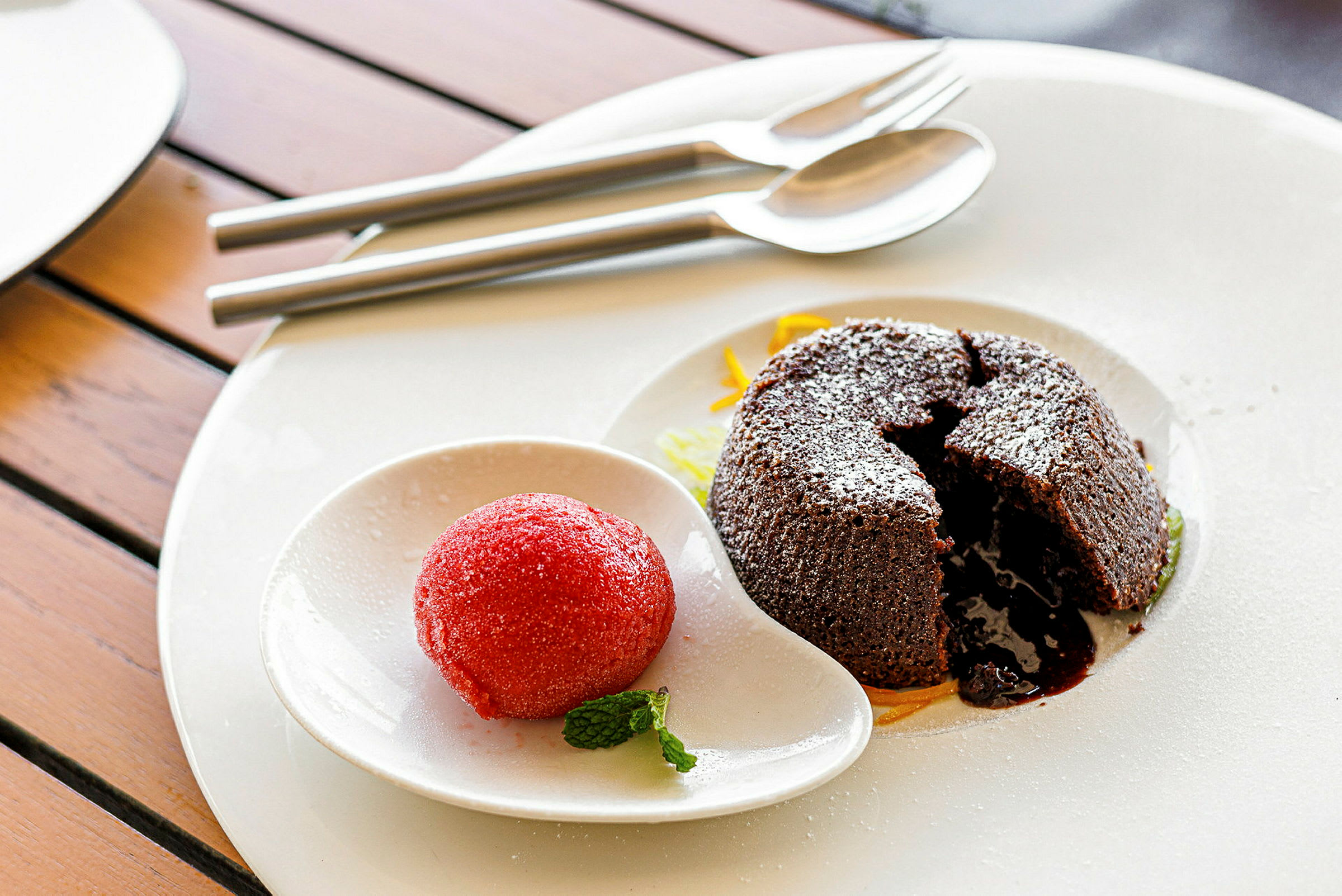 En tallrik med en chokladfondant och en kula sorbet serverad med en mintkvist. (AI-genererad text)