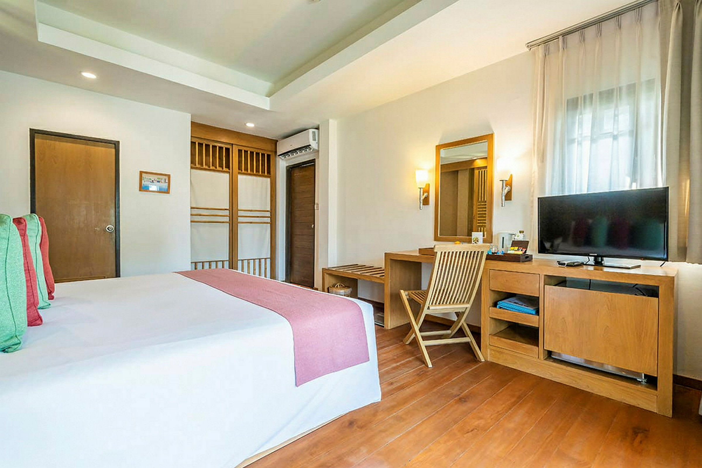 Bild på ett hotellrum med en bäddad säng och ett skrivbord med en spegel och en TV. (AI-genererad text)