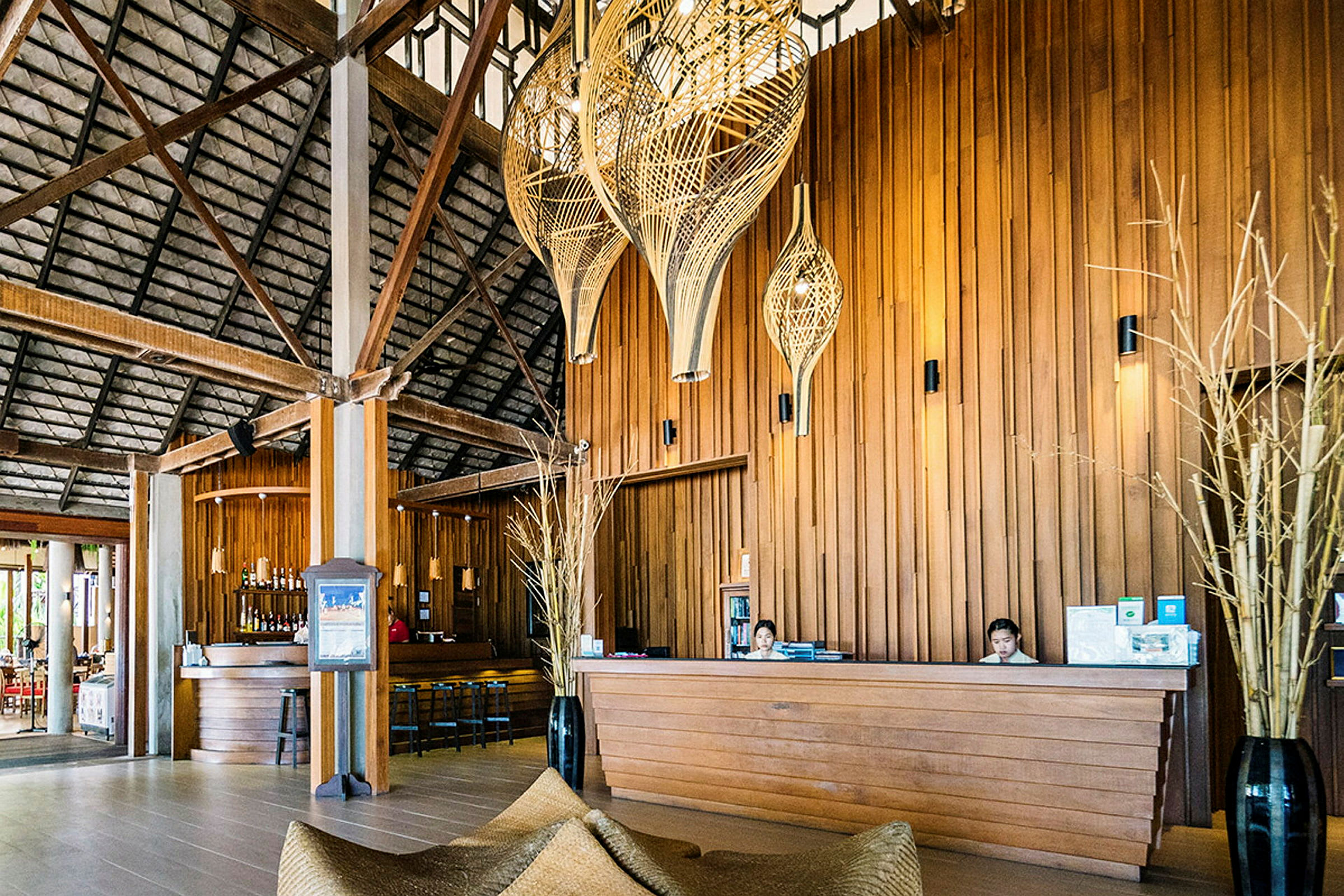 Receptionen på en tropisk resort med träpanel, lyktor och en bar i bakgrunden. (AI-genererad text)