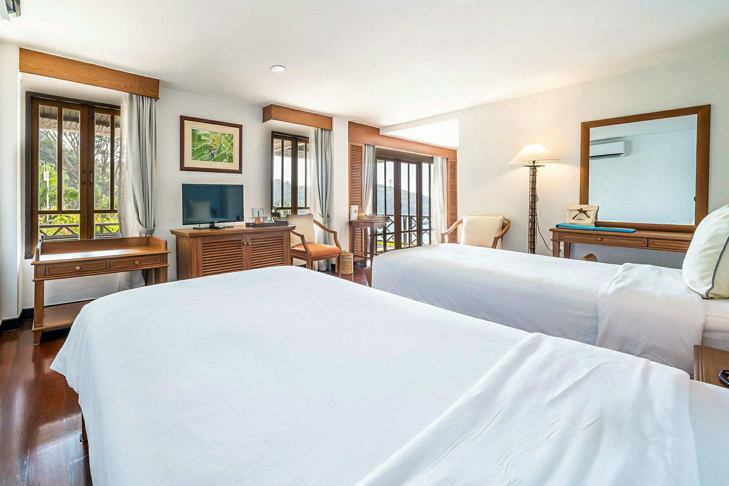 Ett hotellrum med två sängar, ett träskrivbord, en TV och stora fönster med utsikt. (AI-genererad text)