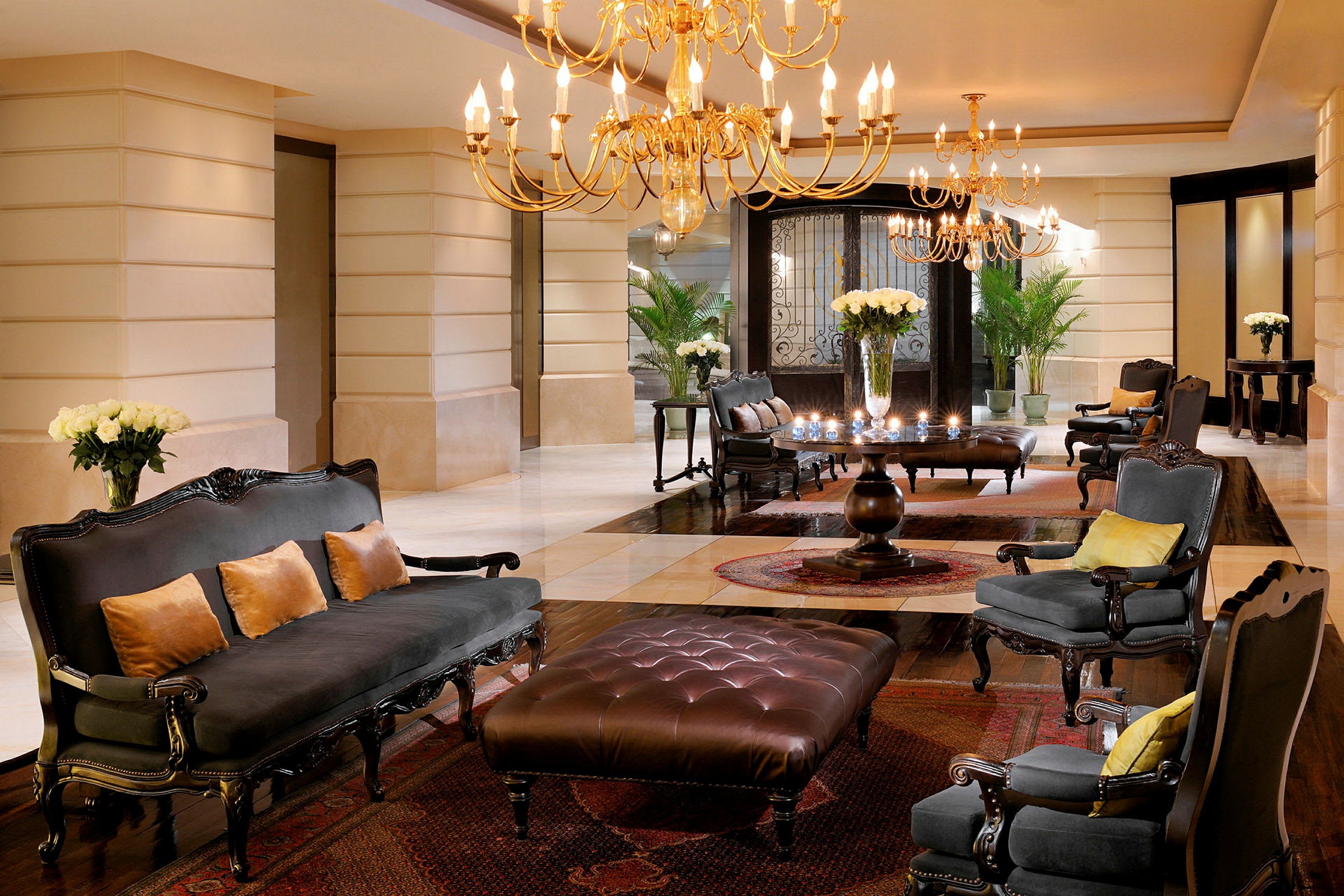 En elegant hotellobby med kristallkronor, bekväma sittmöbler och blommor placerade på bord. (AI-genererad text)