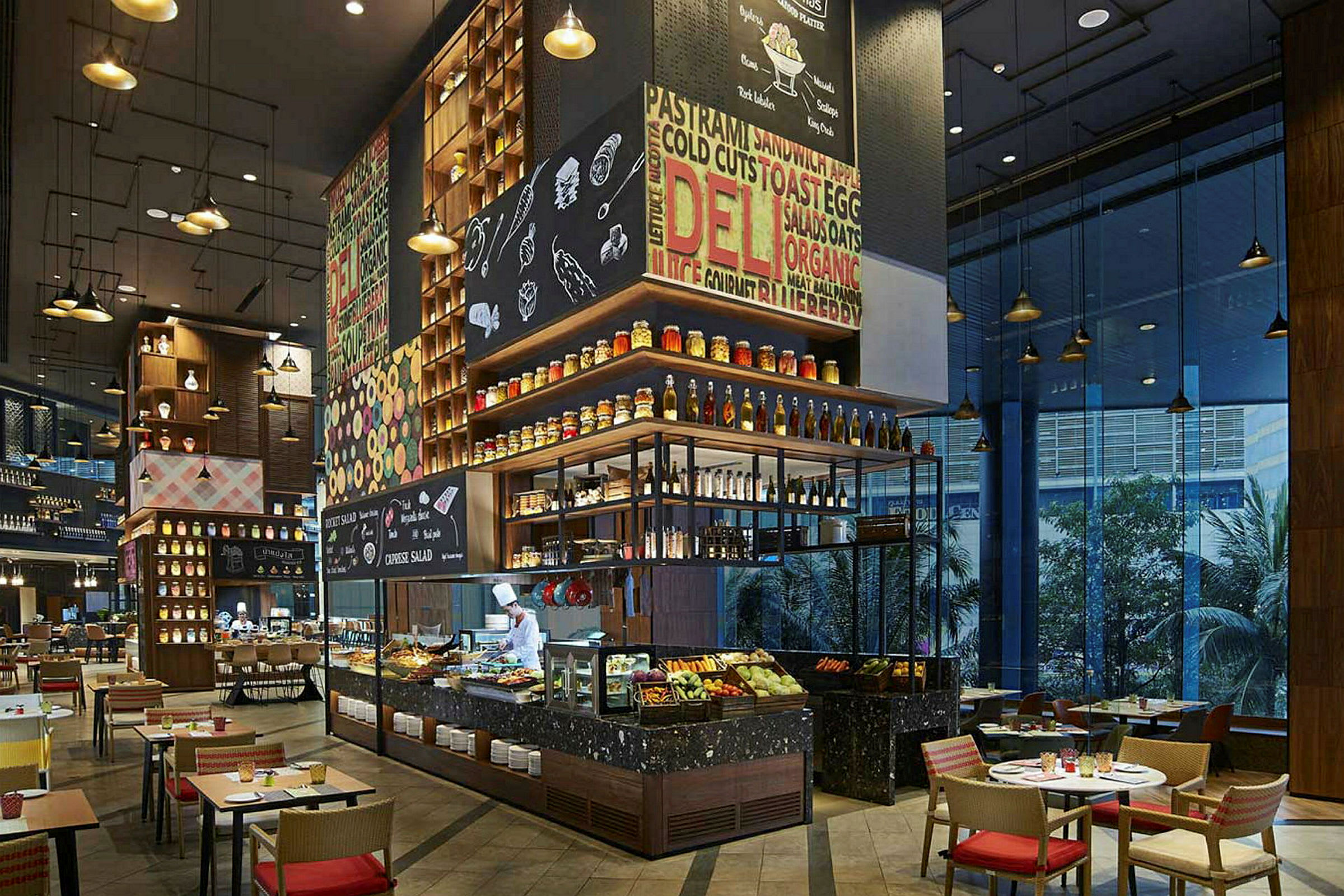 En modern restaurang med stilfull inredning. Det finns ett öppet kök, en buffé med mat och dryck samt bord och stolar för sittplatser. (AI-genererad text)