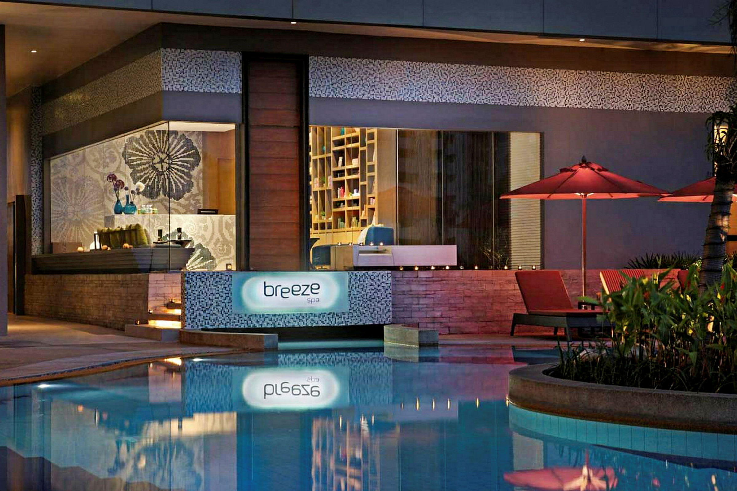 Spaområde med skylten "Breeze Spa", samt röda parasoll och solstolar vid en pool. (AI-genererad text)
