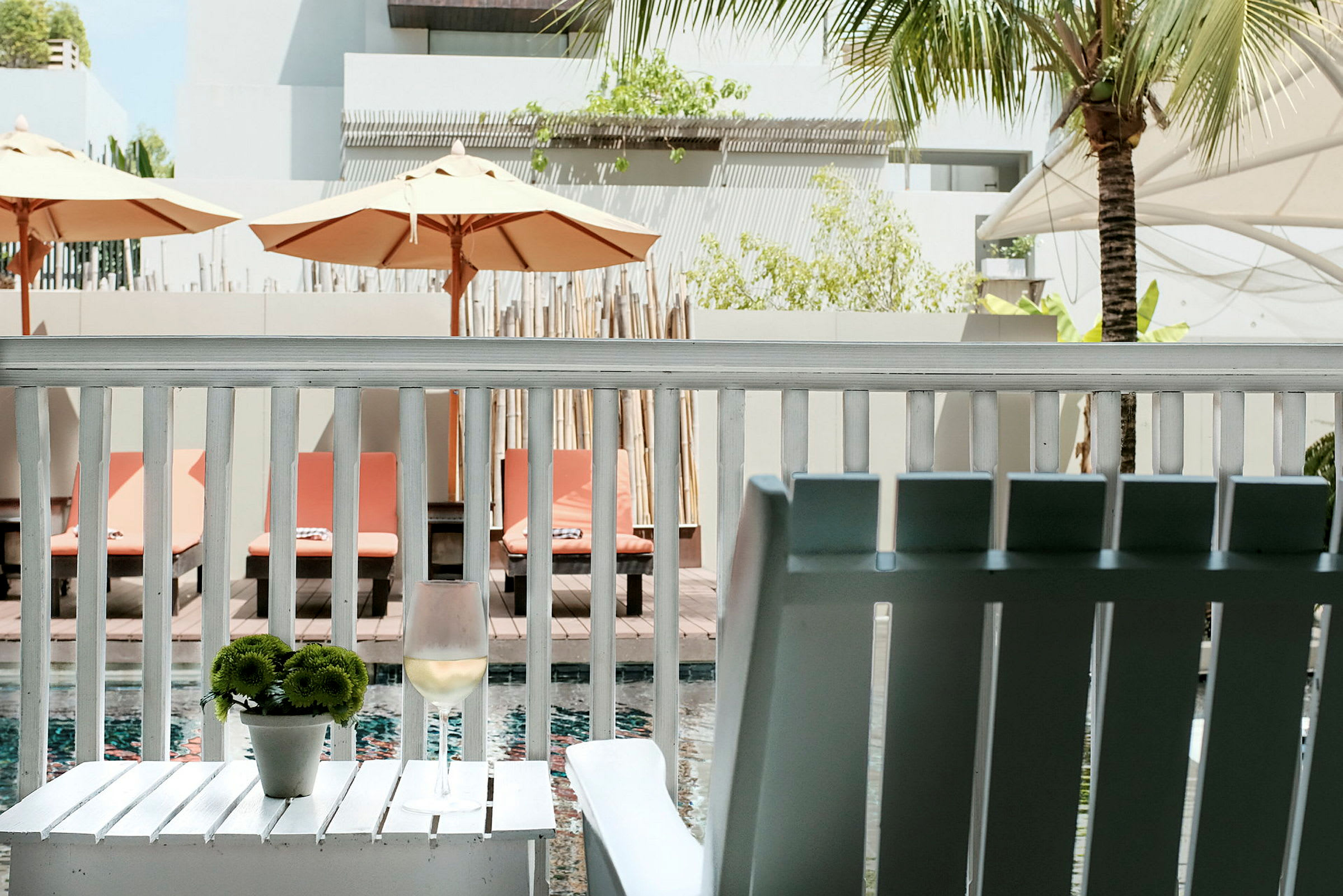 Bild från en veranda med utsikt mot en pool och solstolar. (AI-genererad text)
