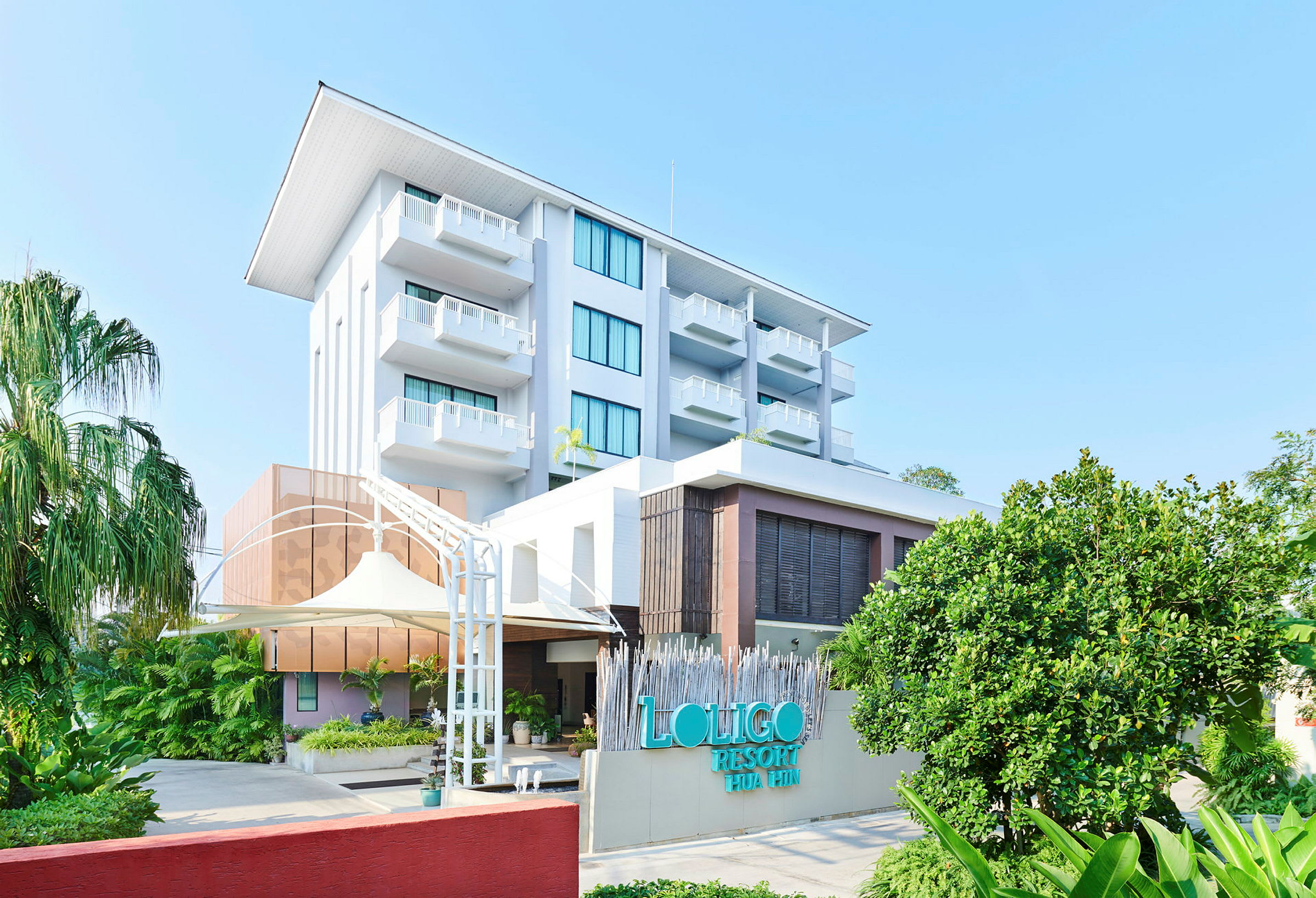 Bild av Loligo Resort Hua Hin med grönska och blå himmel. (AI-genererad text)
