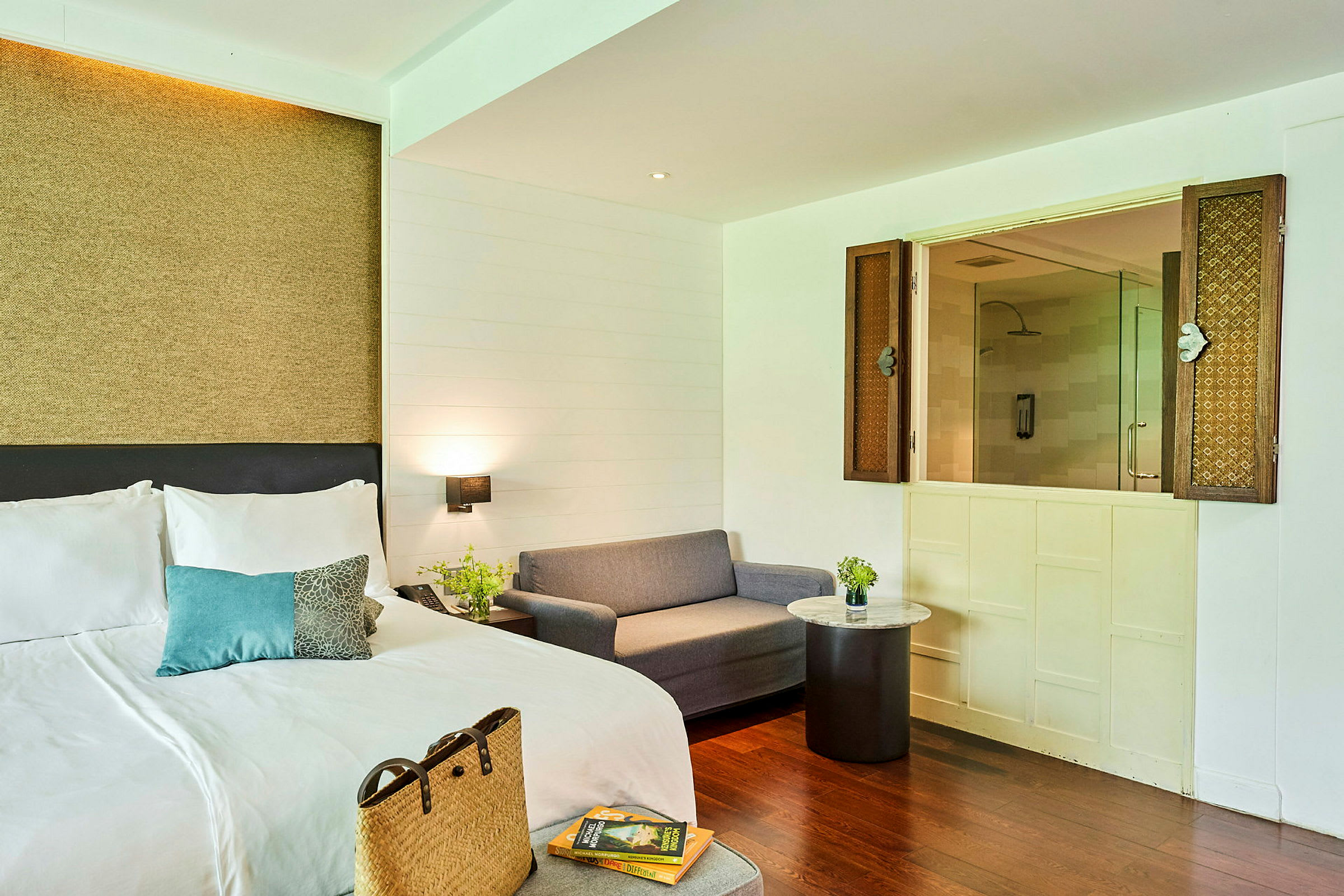 Bild på ett hotellrum med en dubbelsäng, en grå soffa och ett sidobord. (AI-genererad text)