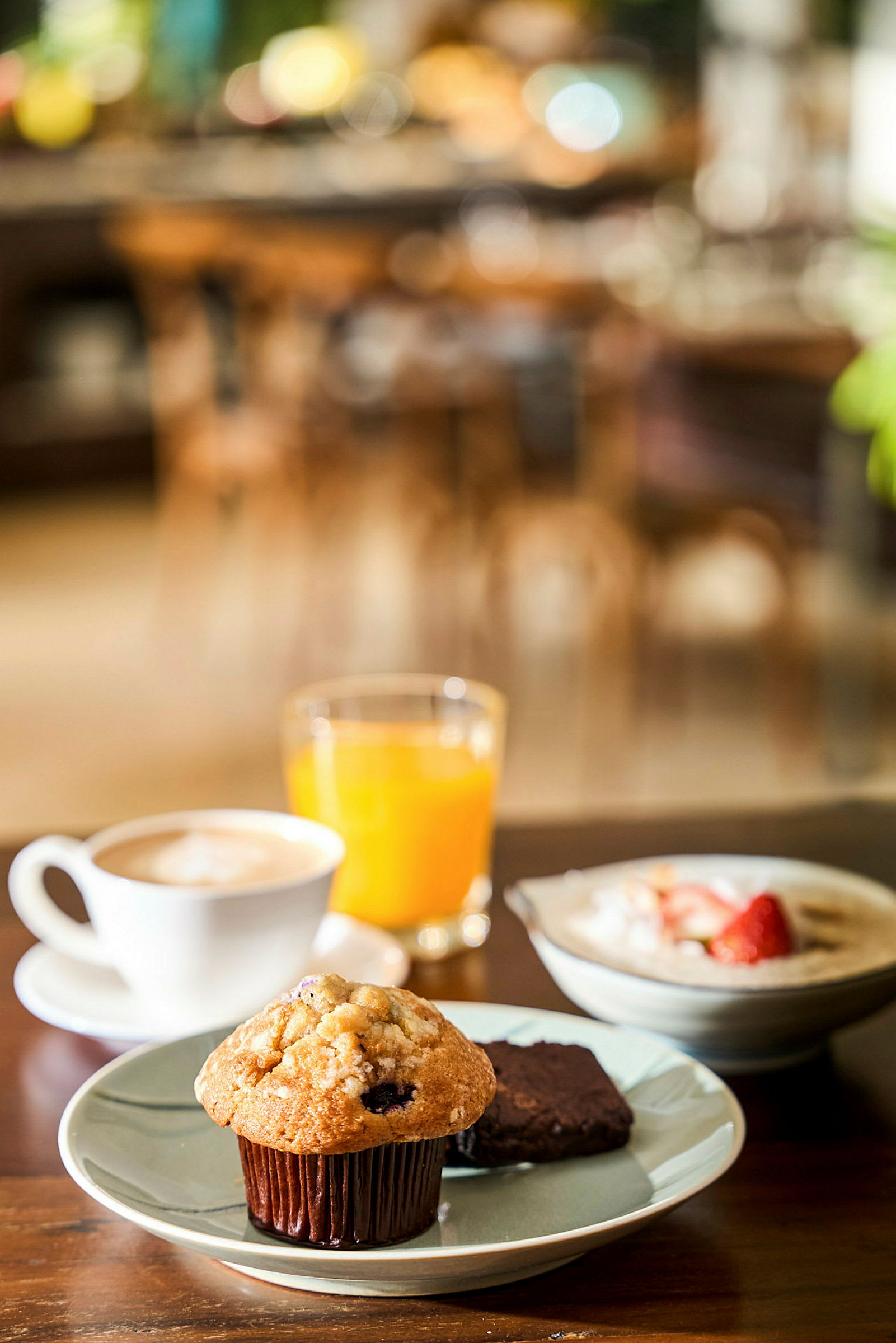 Frukost med muffins, brownie, kaffe, apelsinjuice och tallrik med jordgubbar. (AI-genererad text)