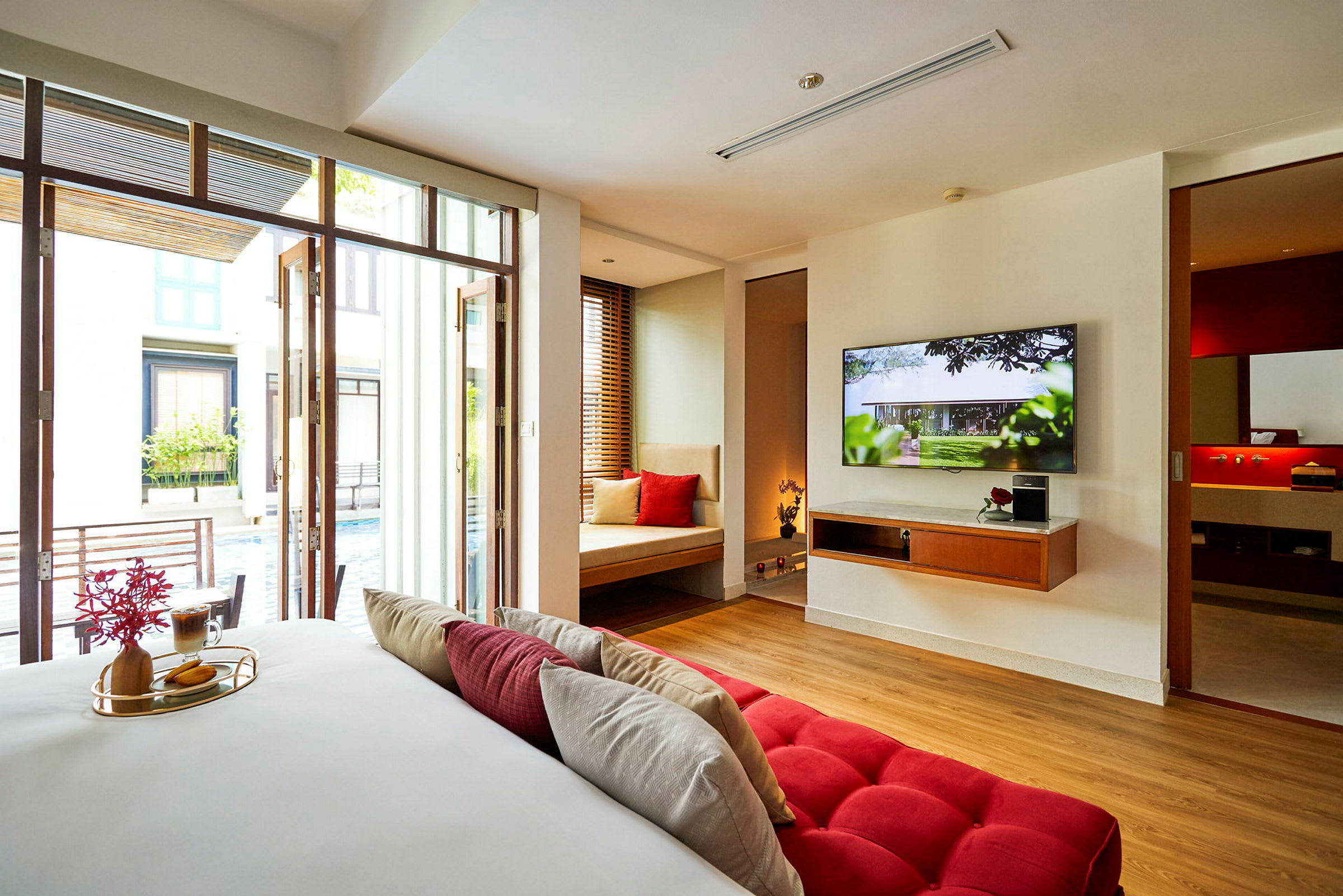 Ett hotellrum med modern inredning, en stor TV och utsikt mot en pool. (AI-genererad text)