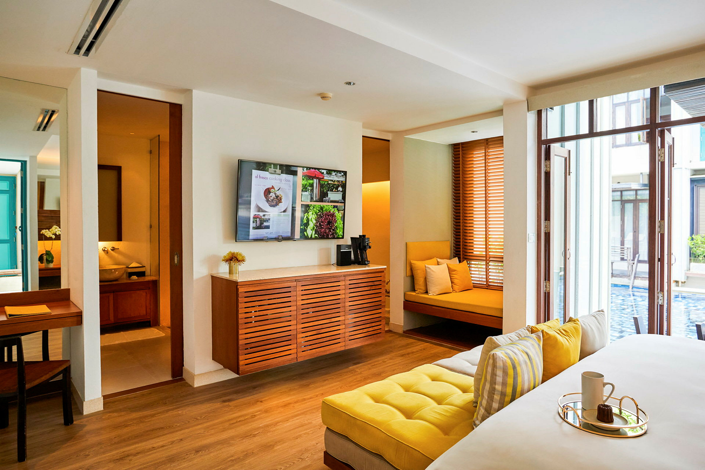Ett modernt hotellrum med sittplatser och utsikt över en pool. (AI-genererad text)