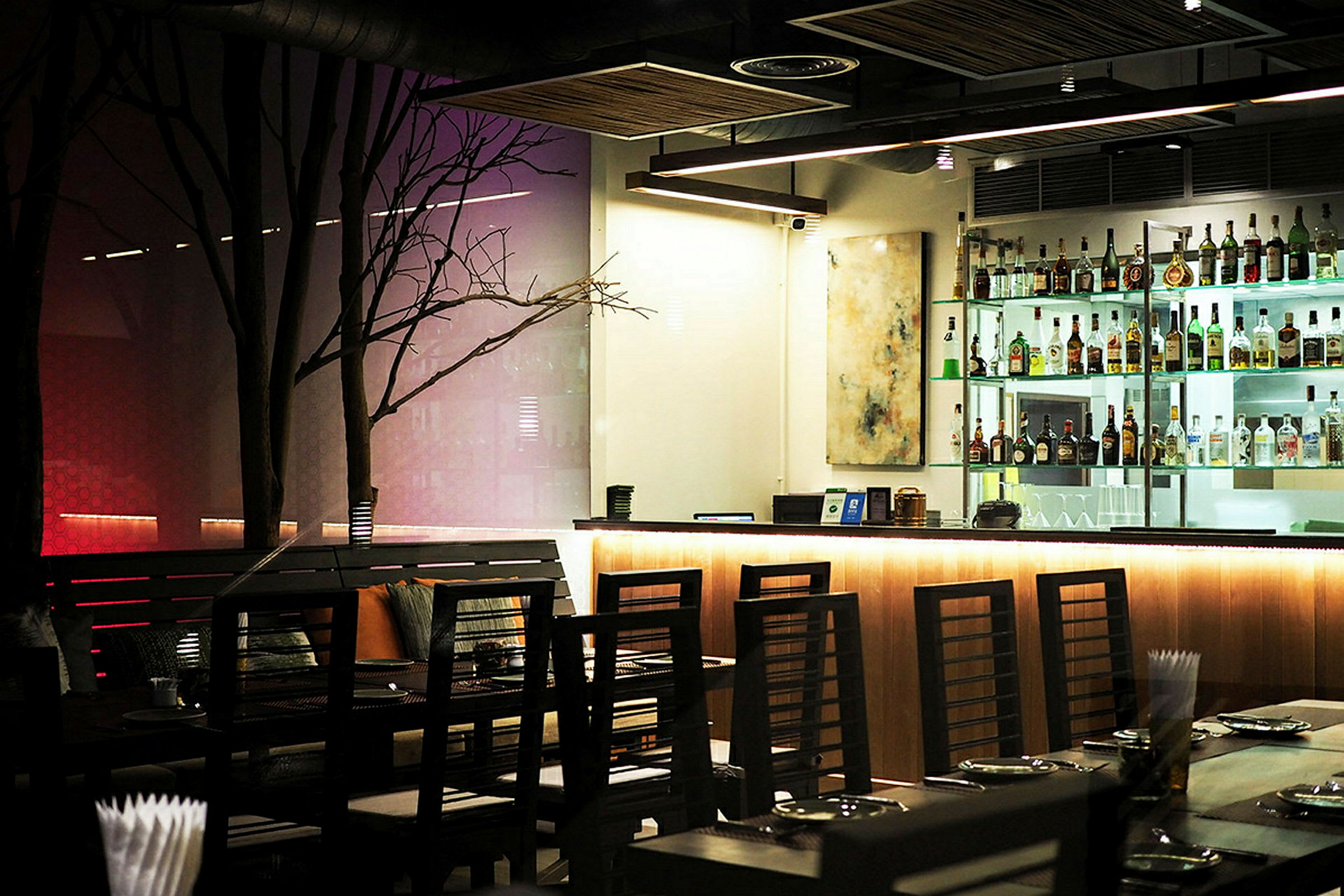 En modern bar och restaurang med upplyst bardisk och stilfulla möbler. (AI-genererad text)