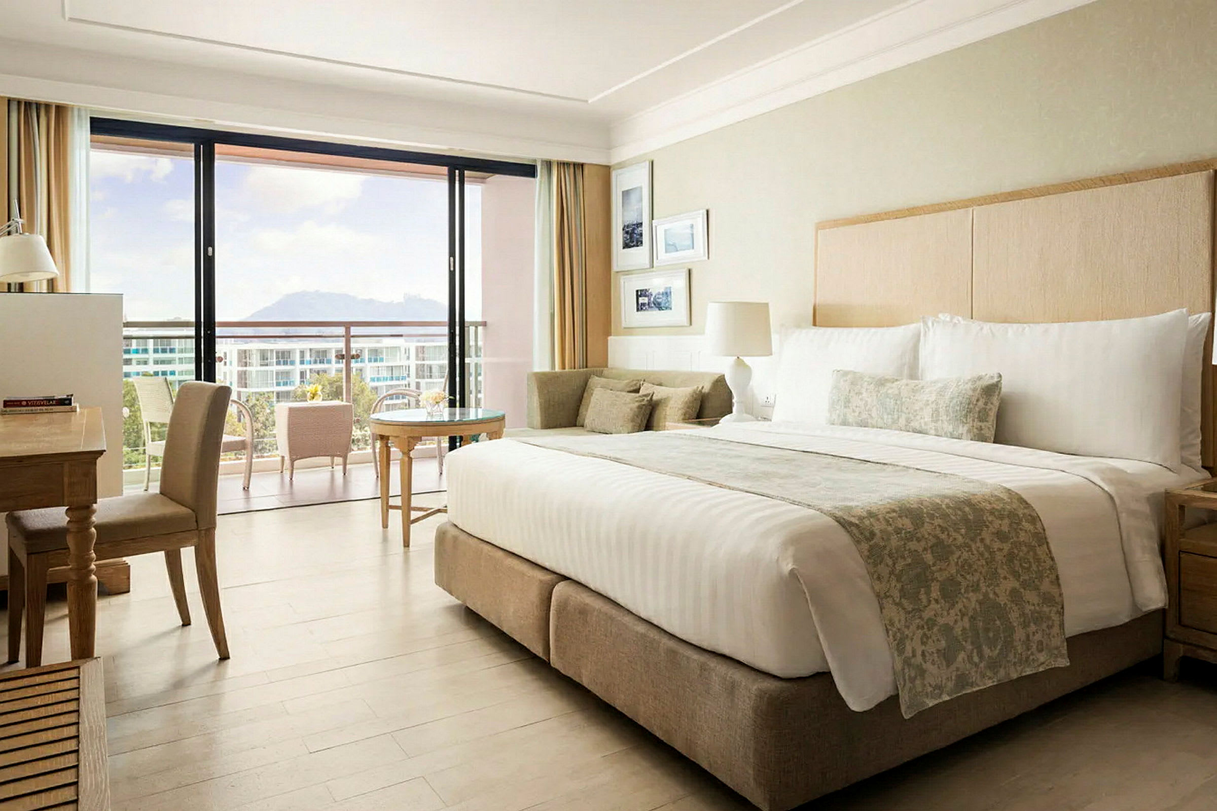 Ett hotellrum med en stor säng, skrivbord, och en balkong med utsikt. (AI-genererad text)